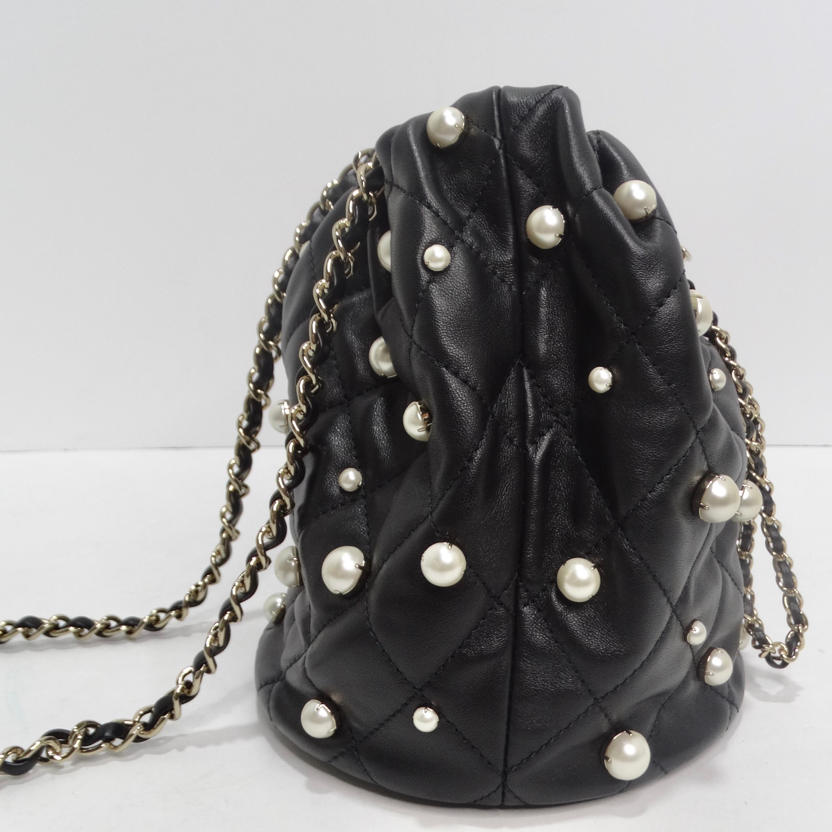 Get your hands on a handbag that's not just an accessory but a work of art - the Chanel About Pearls Black Lambskin Drawstring Bucket Bag. This quilted black lambskin leather bucket bag features a leather threaded drawstring strap, opening to a
