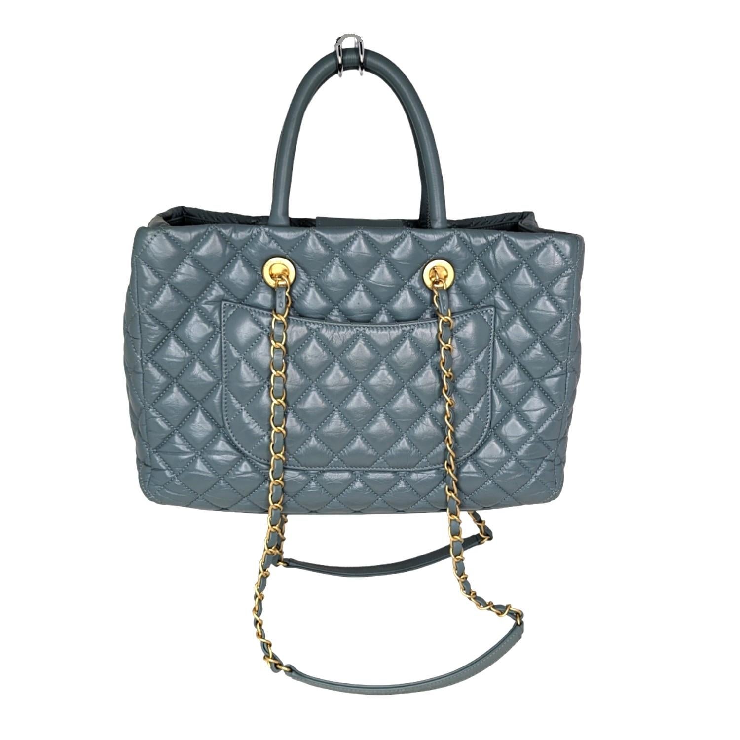 This handbag is crafted of diamond quilted blue aged Calfskin leather. This tote features leather threaded aged gold chain shoulder straps with shoulder pads, rolled top handles, an aged gold Chanel CC logo on the front, a flat pocket on the back.