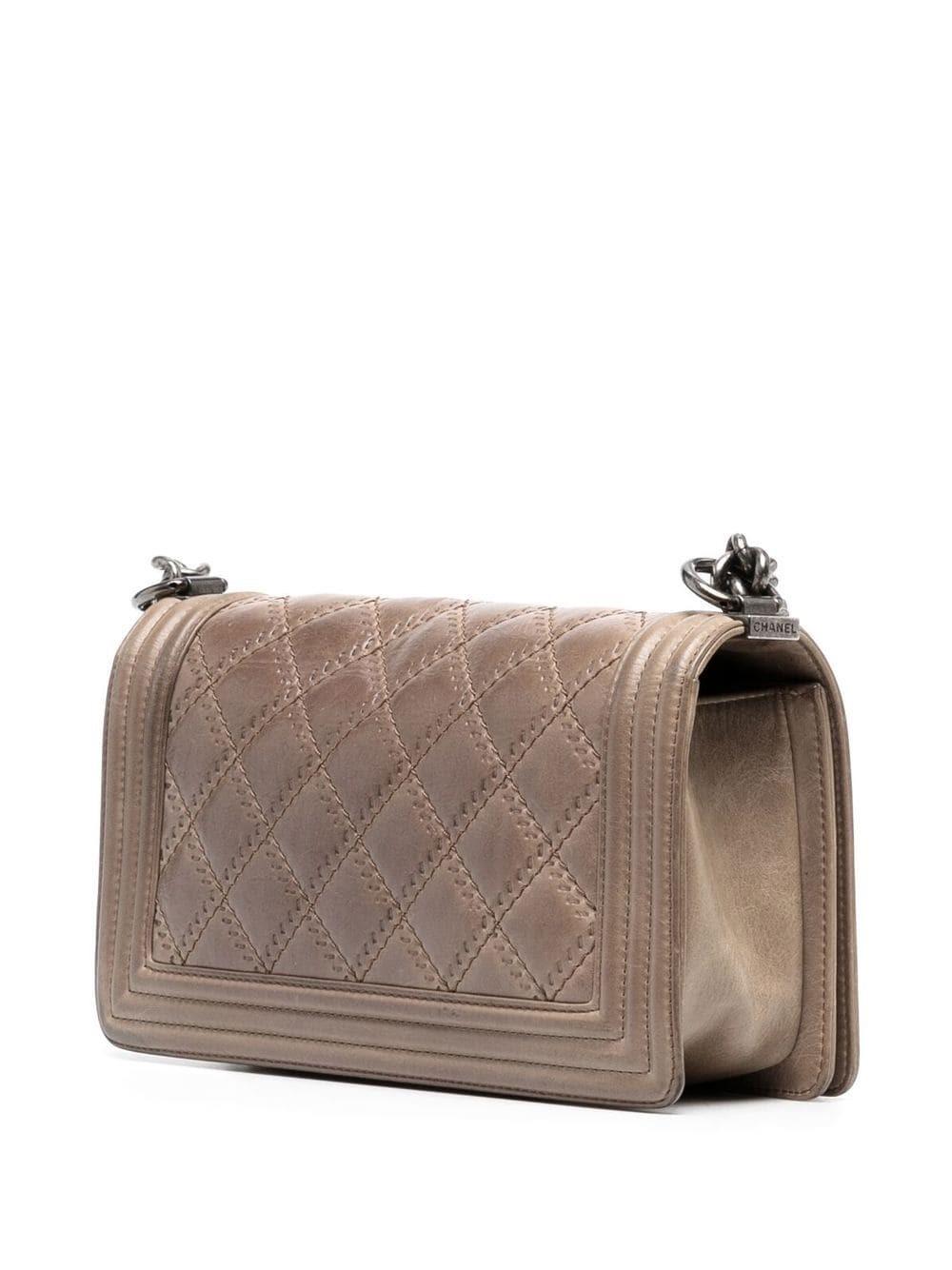 One of the most iconic bags of all time, this Chanel Medium Boy Bag is crafted of quilted aged leather and features an identifiable double C fastening mechanism. The leather chain strap can be adjusted to wear crossbody or thrown on your shoulder.