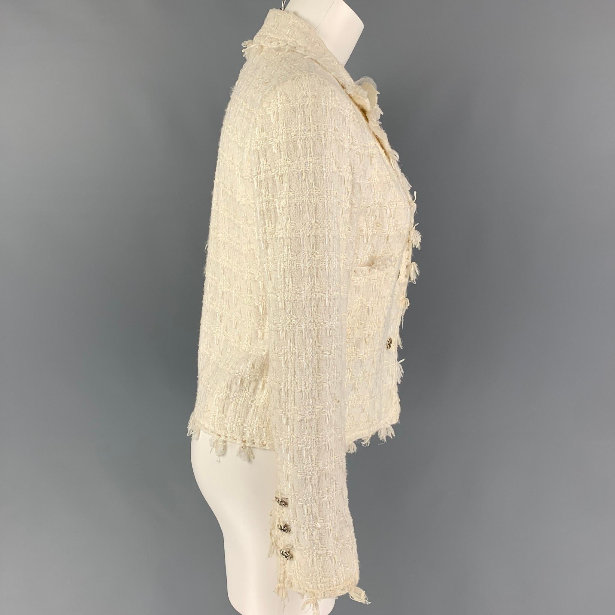 CHANEL jacket comes in a cream boucle cotton blend with a full monogram liner featuring a notch lapel, camelia pin detail, silver tone buttons, and a three button closure. Made in France. 

Very Good Pre-Owned Condition. Small mark at