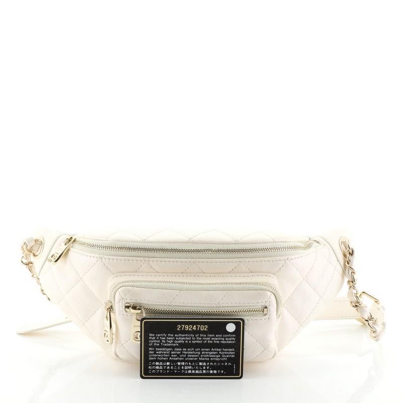 This Chanel All About Waist Bag Quilted Iridescent Caviar, crafted in white quilted iridescent caviar leather, features woven-in leather chain link and leather waist strap, exterior zip pockets, and gold-tone hardware. Its top zip closure opens to a