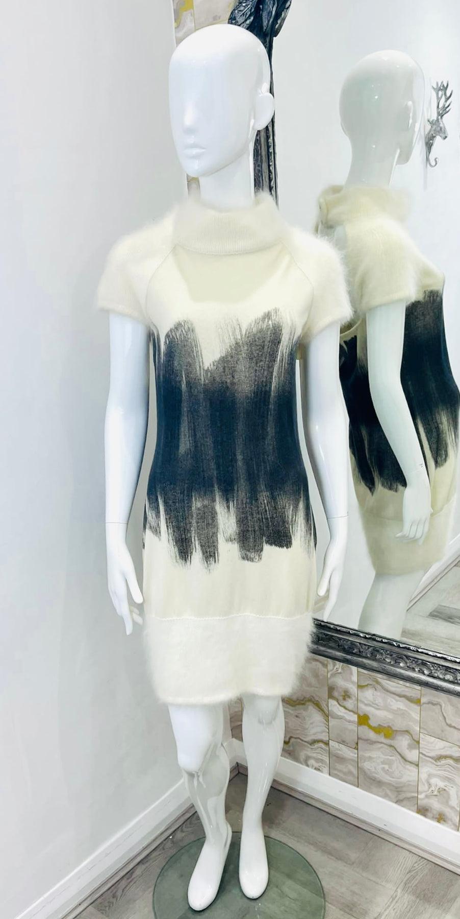 Chanel Angora & Cashmere Dress

Ivory mini jumper dress with rolled neckline and short sleeves. Abstract brush design around the centre part of the body, wide ribbed hem. Features open back and 'CC' logo pearl and crystal embellished button closure.