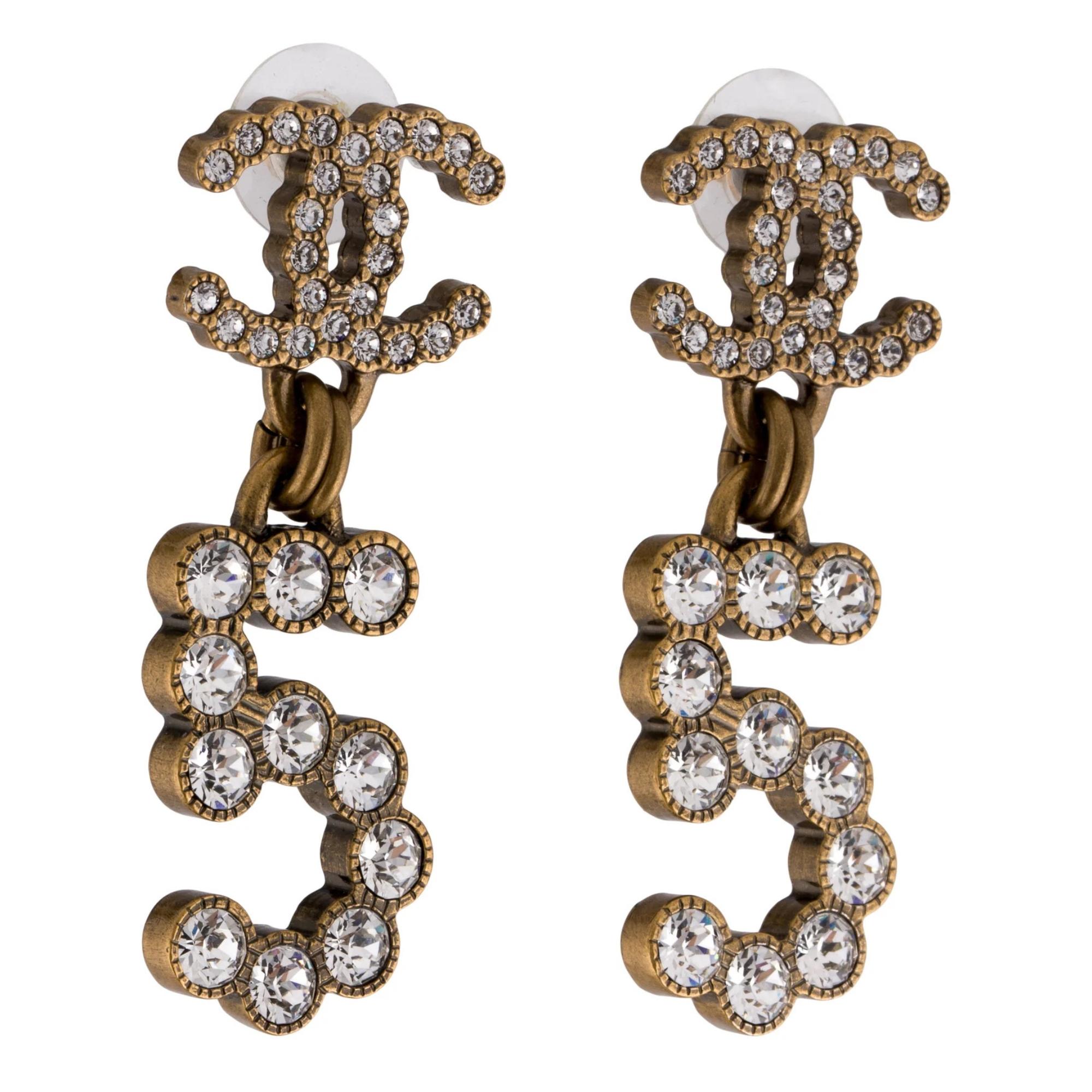 The earrings feature an antiqued gold tone finish, strass and a handing °5 pendant. The earrings clip on for the CC logo clasp. From the Spring/Summer 2020 Collection by Virginie Viard.

Antiqued-gold-tone Metal & Strass.
Marks: Designer Signature,
