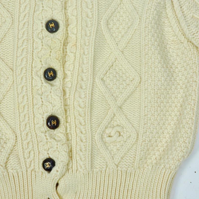 A wonderful Chanel  knitted cardigan in pure wool with distinctive leather buttons each embossed with gold CC logo. 
The traditional Aran pattern runs through the knit and a cleverly knitted Chanel logo has been knitted into the bottom left hand