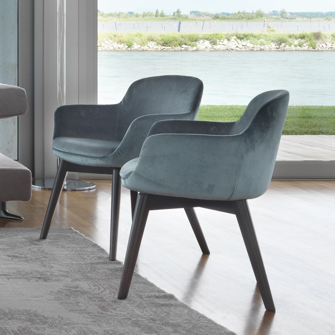 This armchair embodies the concepts of simplicity and elegance. Covered in aquamarine velvet, its curved, sinuous lines highlight its design. It features a steel structure, cold-moulded polyurethane foam and wooden inserts. Its beechwood legs can be