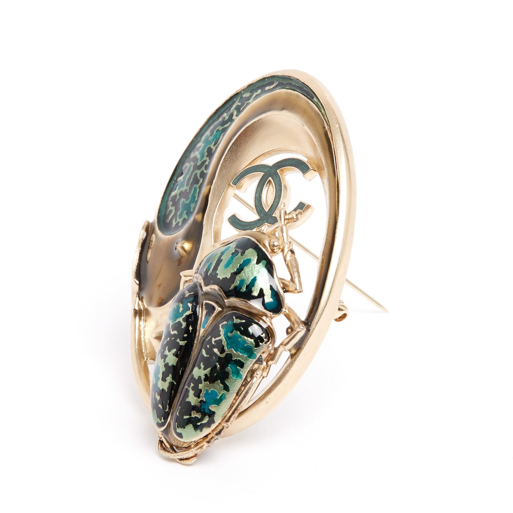 Large Chanel brooch inspired by Art Nouveau in matte (pale) gold metal and enamel in different tones, with a scarab motif and a CC logo. Width 5 x height 7.2 cm. The brooch comes from the (very) private sales of the house of Chanel and it does not