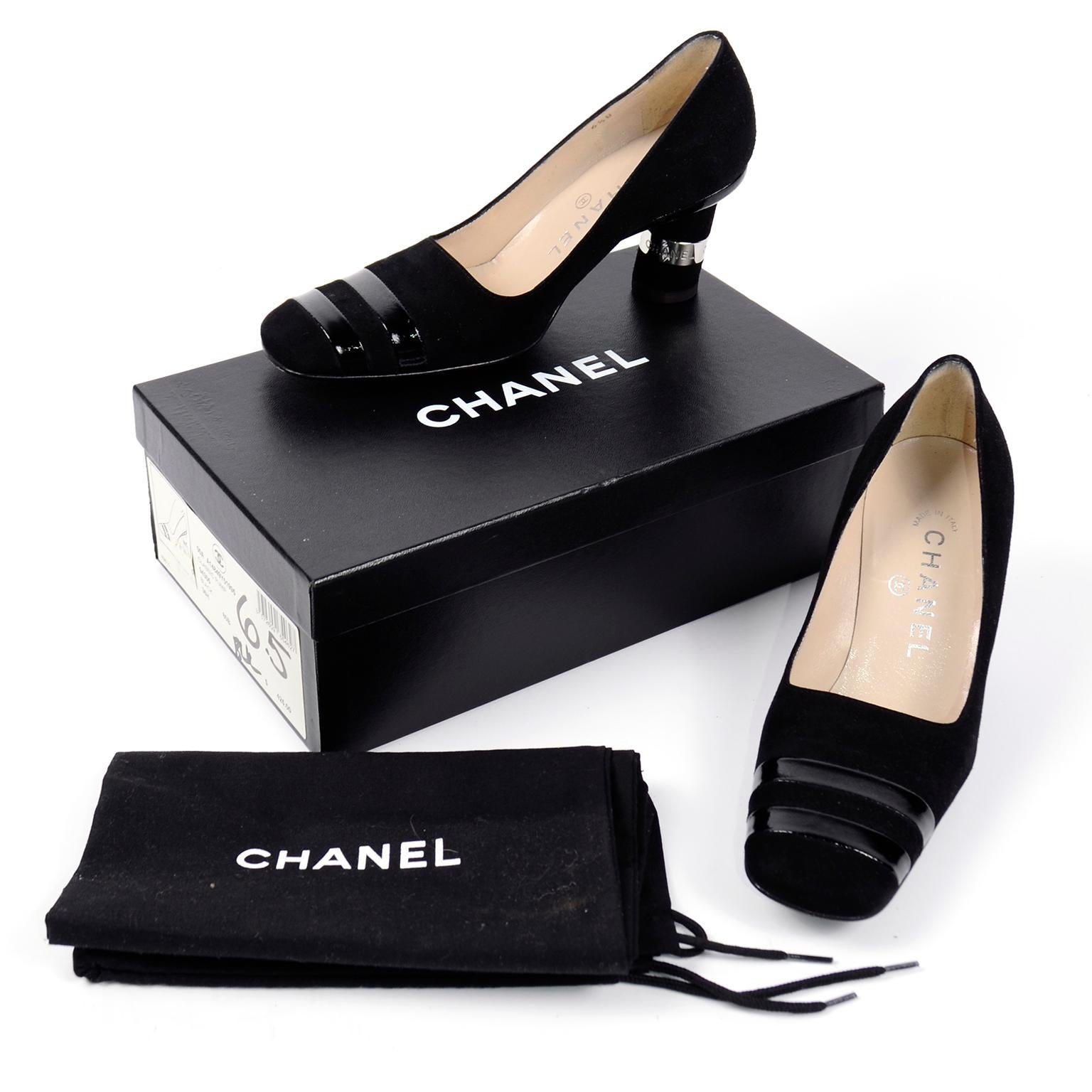 These vintage Chanel Autumn Winter 2000 black suede pumps have fabulous cylindrical block heels with Chanel marked silver metal bands. There are two horizontal patent leather bands across the toe boxes and the shoes have a gently squared toe. These