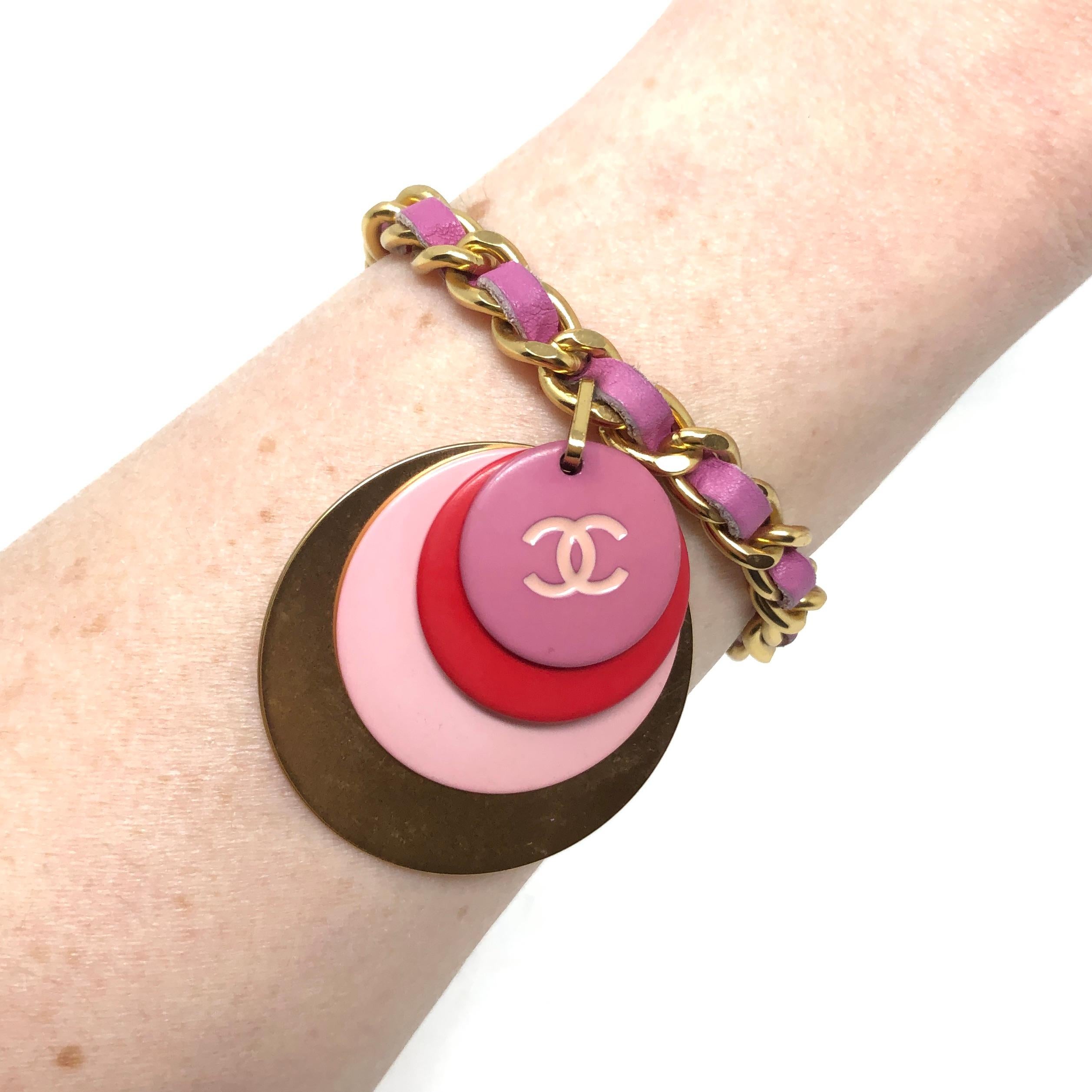 This chic bracelet was created by Chanel in 2001.

Condition Report:
Excellent

The Details...
This bracelet features a gold plated curb link chain threaded with a pink leather strap. Suspended from the chain is a charm, comprised of 3 pink and red