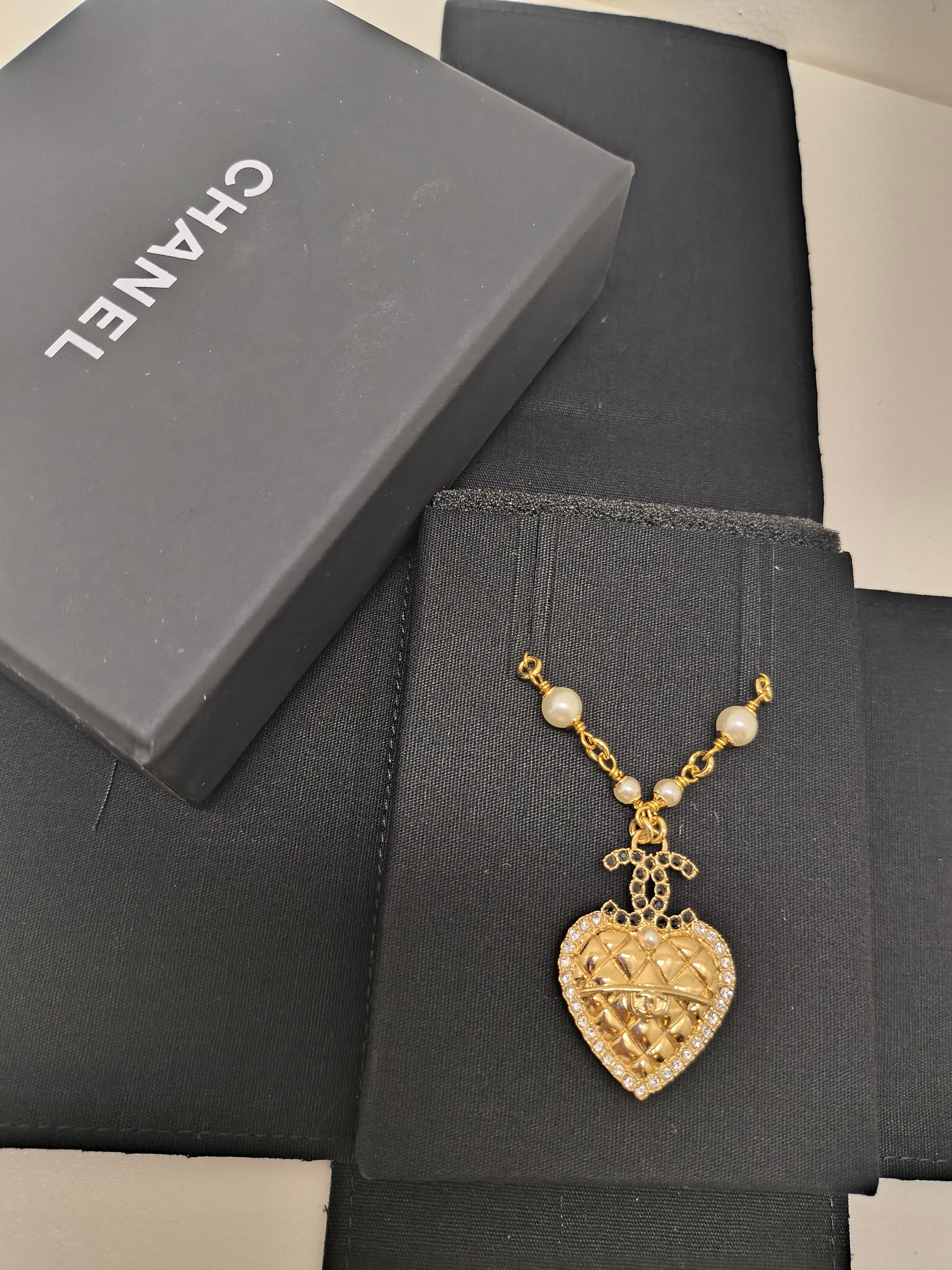 Questa collana, appartenente all'ambita Collection'S B24 di Chanel, emana una raffinatezza romantica con dettagli tipici della Maison. Il design è caratterizzato da un ciondolo trapuntato a forma di cuore, incorniciato da cristalli scintillanti e