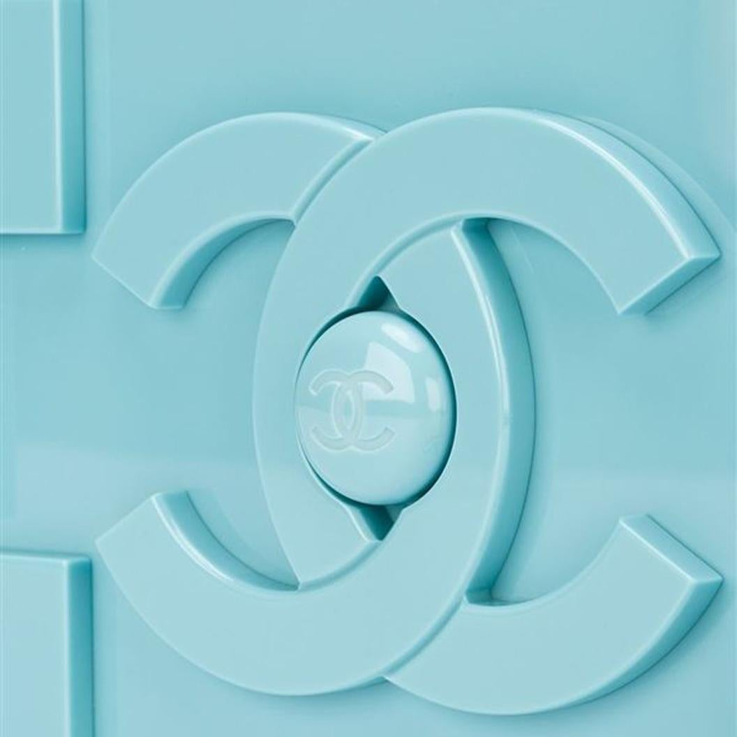 El juguetón bolso de lego de Chanel se renueva con fuerza. Este raro y coleccionable bolso de mano diseñado en plexiglás azul bebé presenta llamativos logotipos en ambos lados de su estuche rígido y su cierre de presión en la parte superior. Con una