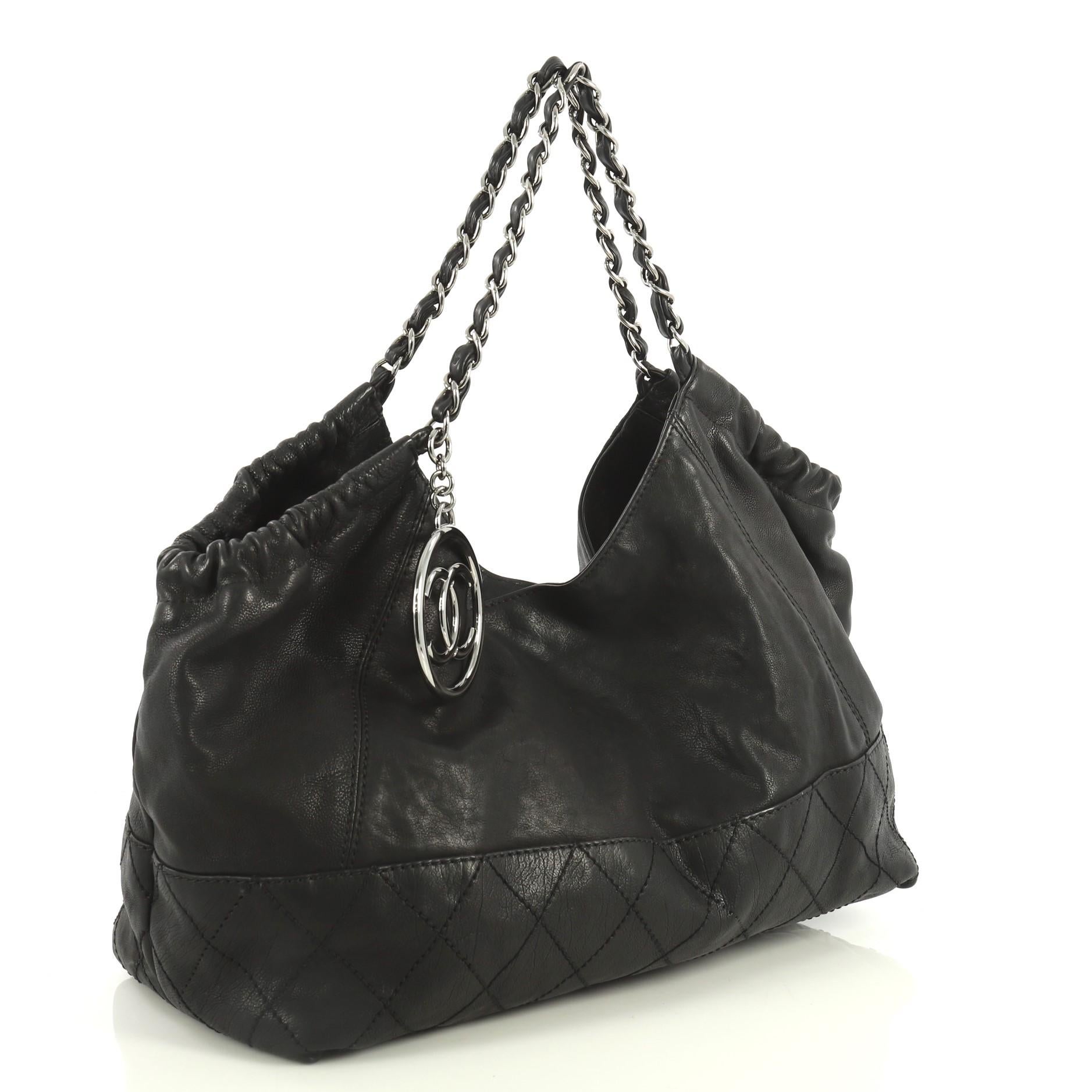 This Chanel Baby Coco Cabas Quilted Leather Large, crafted in black quilted leather, features woven-in leather chain handles and silver-tone hardware. Its magnetic snap closure opens to a black suede interior with slip and zip pockets. Hologram
