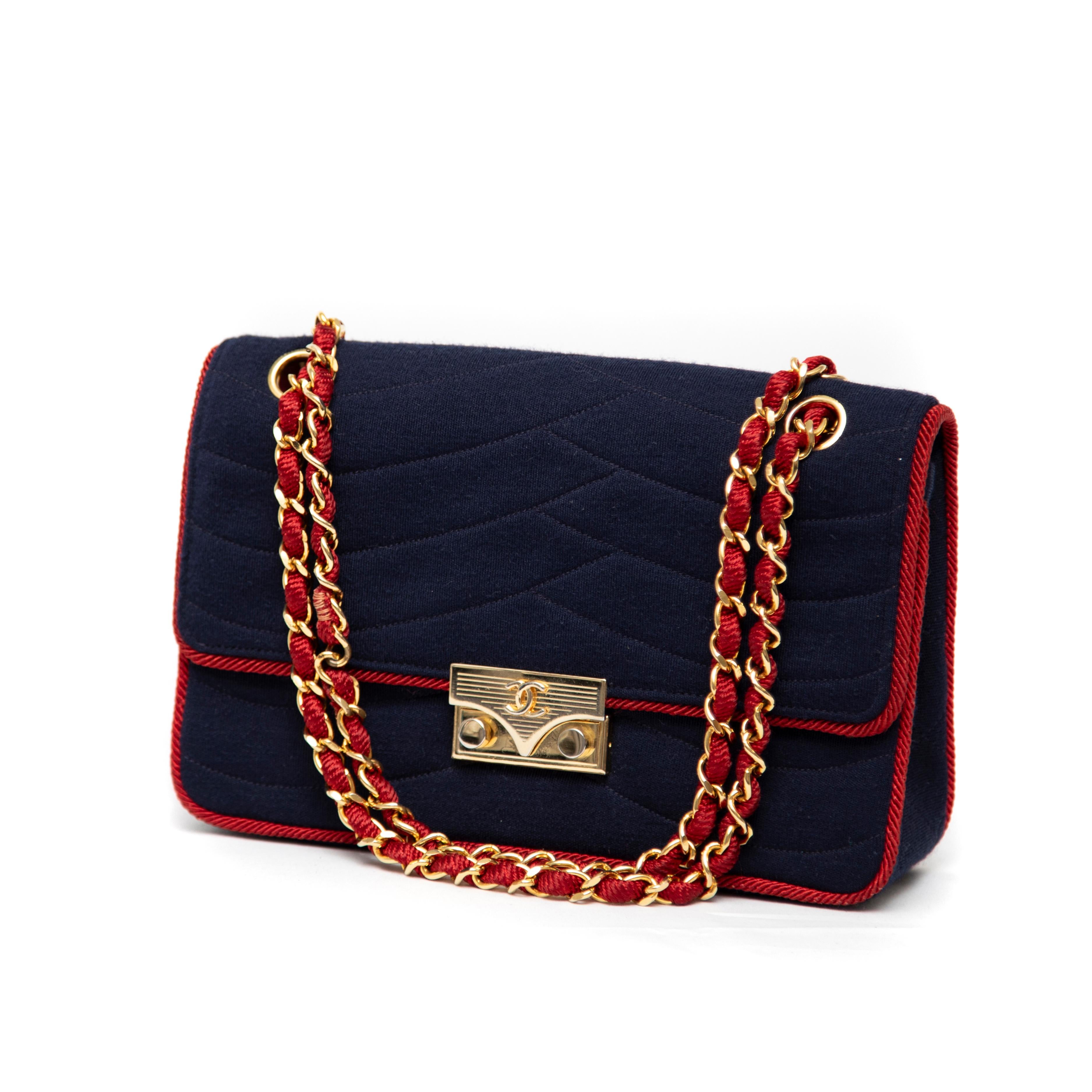 The Chanel 225 Navy Jersey with Red Rope Piping Bag is a stunning accessory that perfectly embodies the brand's signature blend of elegance and playful charm. Crafted in the 1970s from soft navy jersey, this bag features distinctive red rope piping