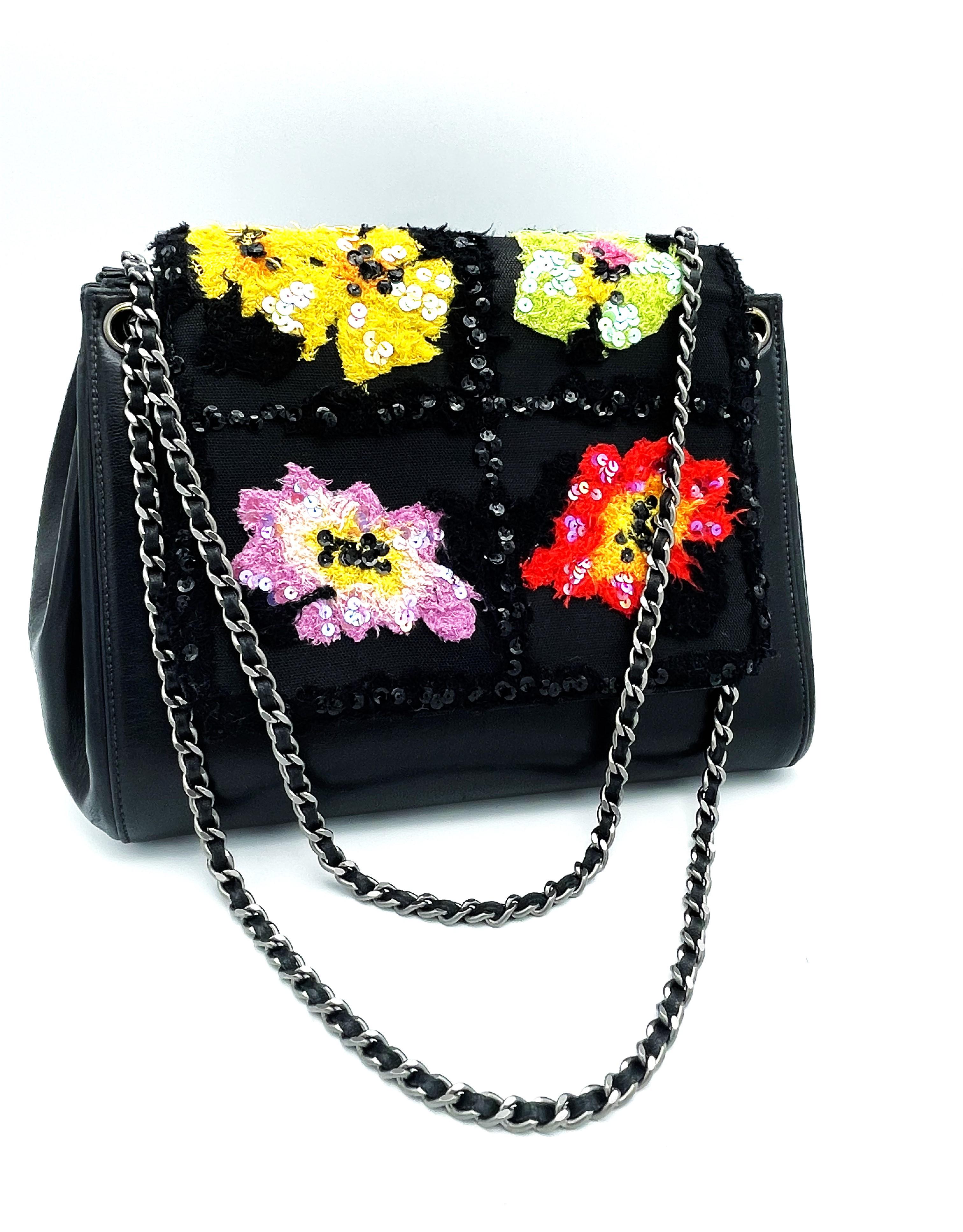 A totally extraordinary Chanel bag in the form of an accordion, which makes it very spacious and has a large opening. The cover of this bag is provided with 4 colorful fabric flowers, which are framed by black sequins, which is also the unusual