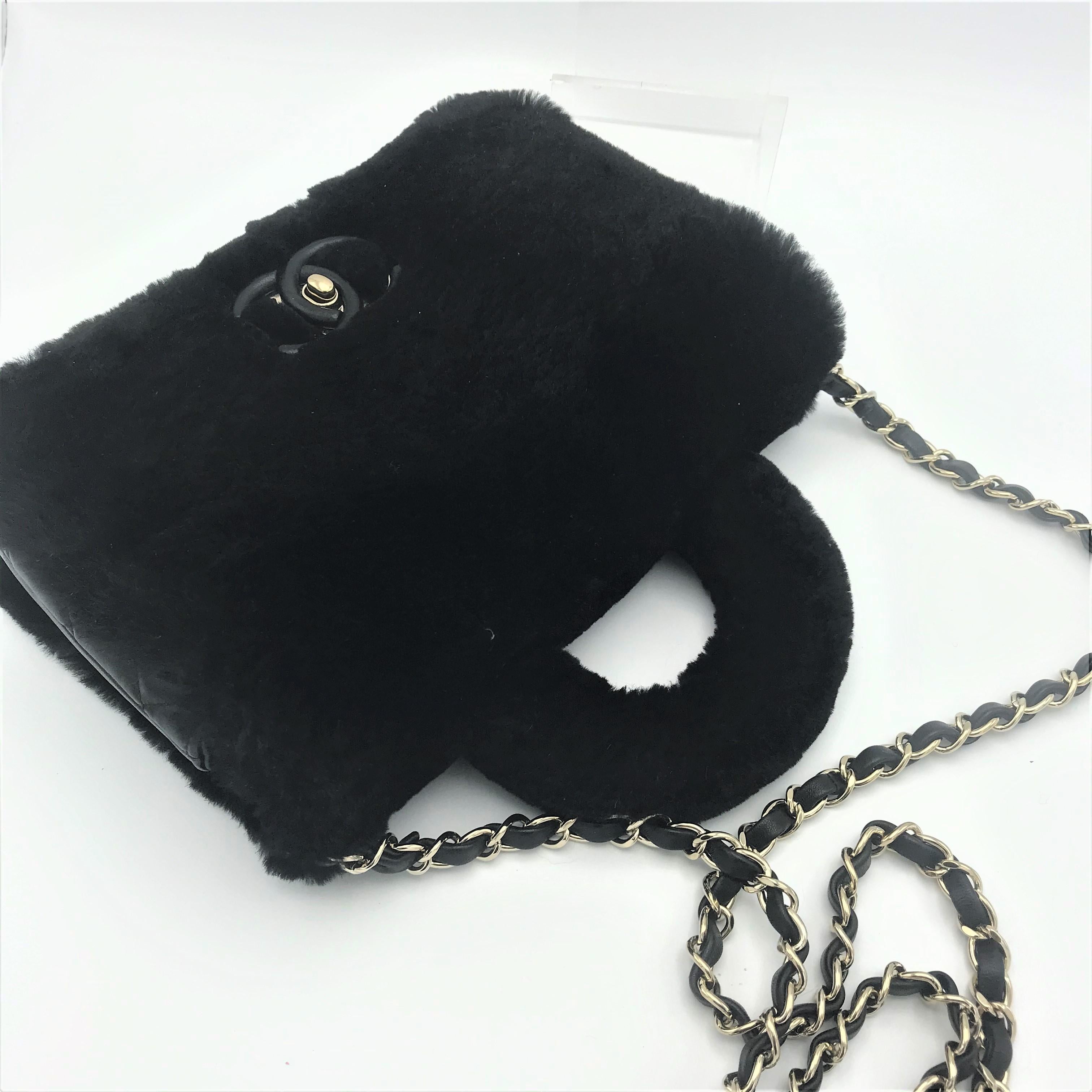 Una bellissima borsa Chanel nera di piccole dimensioni (Made in France) in pelle di vitello trapuntata nera di 2 cm x 2 cm.  La parte anteriore e posteriore della borsa è realizzata in shearling nero lucido.

La borsa ha un piccolo manico e il