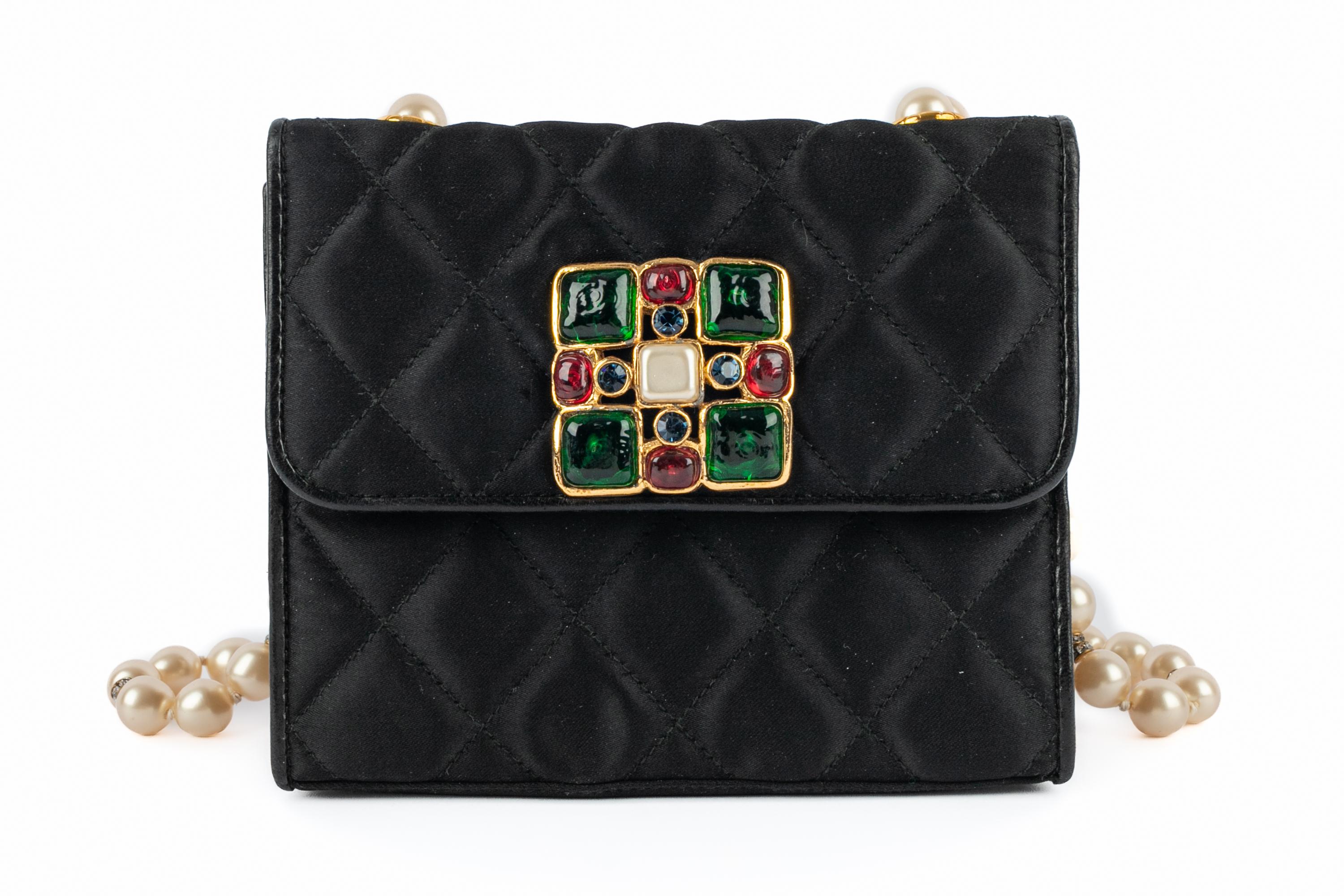 CHANEL - (Made in France) Tiny quilted black satin bag ornamented with a golden metal jewelry, a costume pearly cabochon, and  colorful glass paste cabochons. Handle made of costume pearls and rhinestoned rings. Leather interior. Serial number: