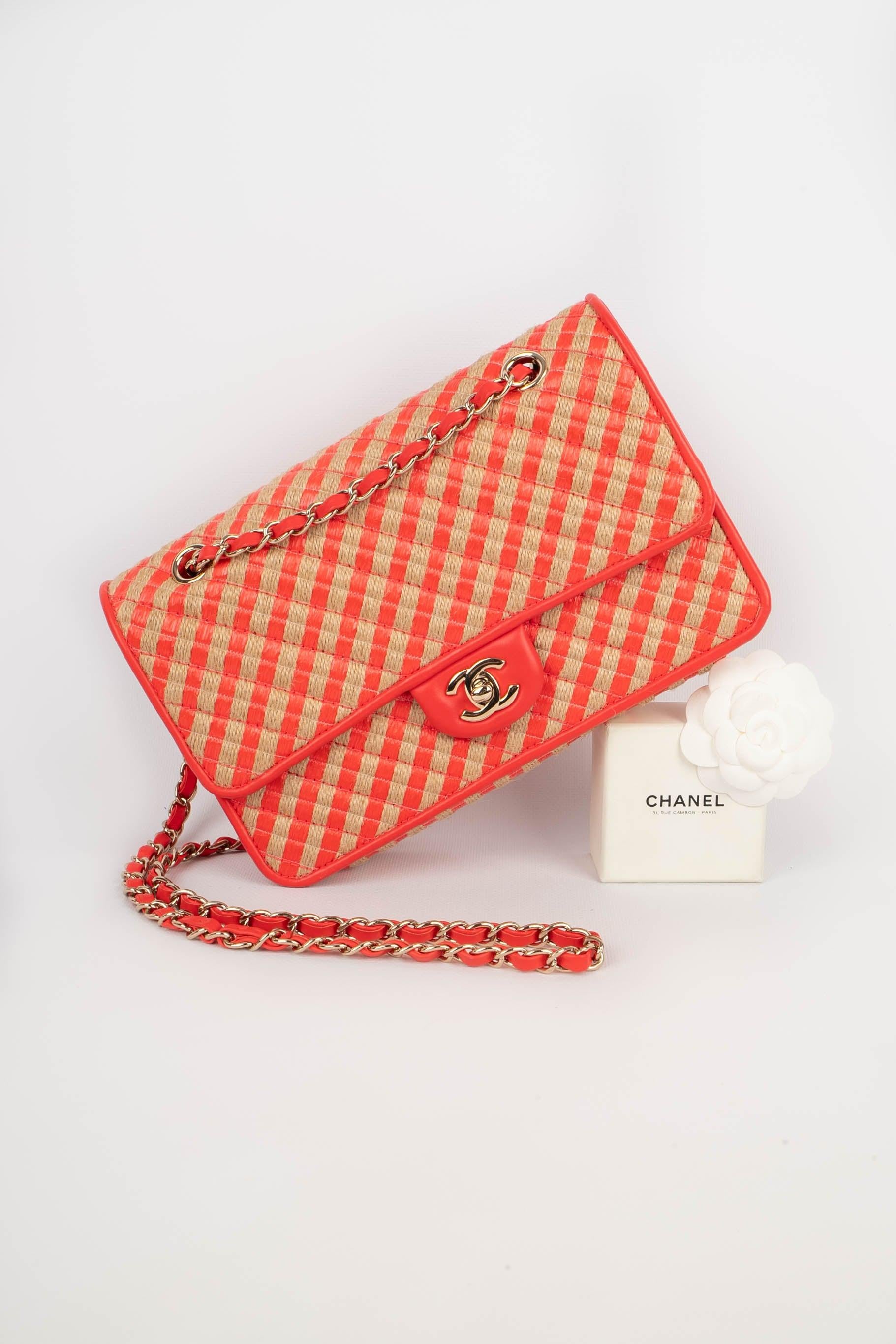 Chanel - (Made in France) Bag made of natural rope, vermilion raffia,and leather, with a champagne metal 'CC' fasterner on the flap, and a handle interlaced with a chain. Piece with a serial number and a certificate of authenticity. 2021