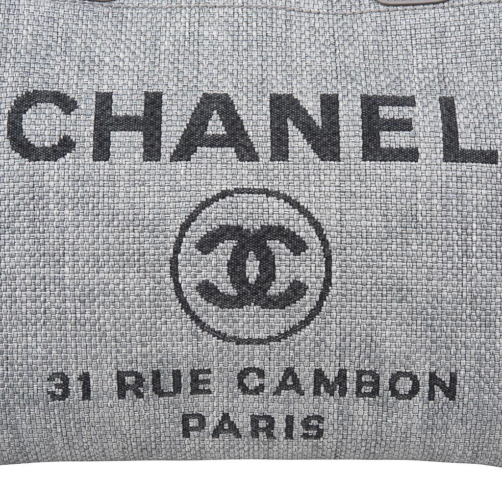 Guaranteed authentic Chanel small Deauville grey and black tote bag.
Body is woven fine raffia in medium grey with Chanel, iconic CC logo and Rue Cambon address in black. 
Signature threaded chain with canvas.
Magnetic closure. 
Interior is lined in