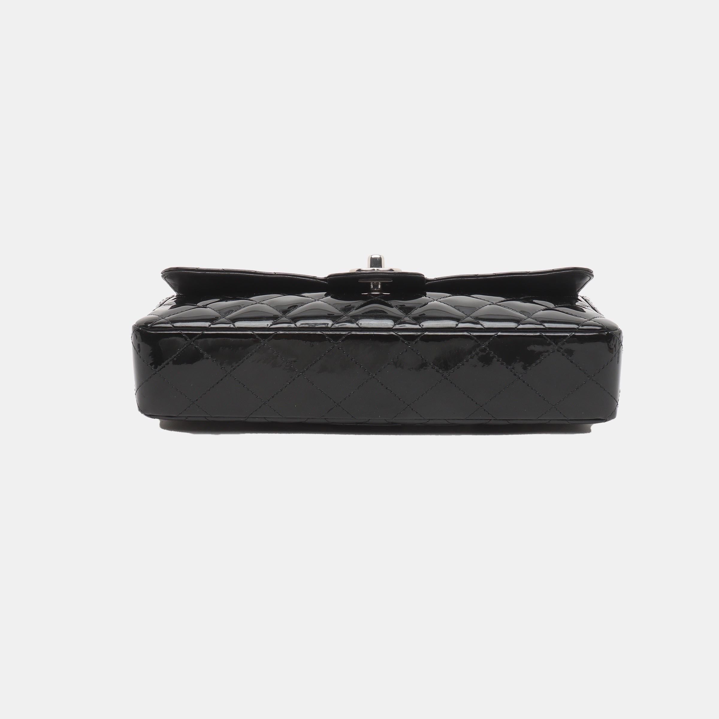 This Chanel baguette shoulder bag showcases a stunning black patent leather, complemented by sleek silver hardware. Slightly shorter than the classic flap, this bag boasts an elegant design that is perfect for wearing over the shoulder. Its double
