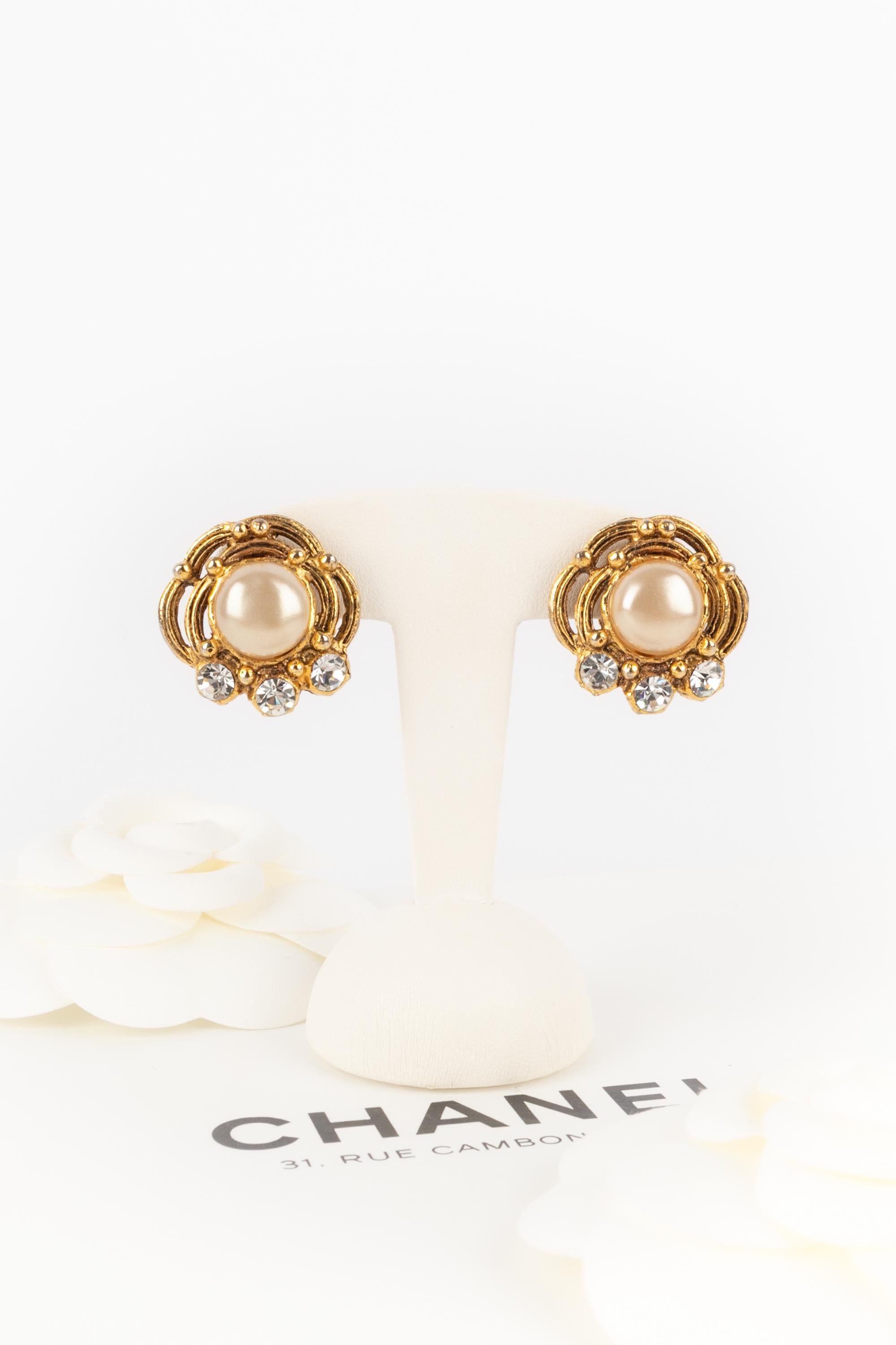 Chanel- (Made in France) Clip-on gilded metal earrings decorated with a pearly cabochon and rhinestones.

Additional information:
Dimensions: 2.5 W x 2.5 H cm (0.98