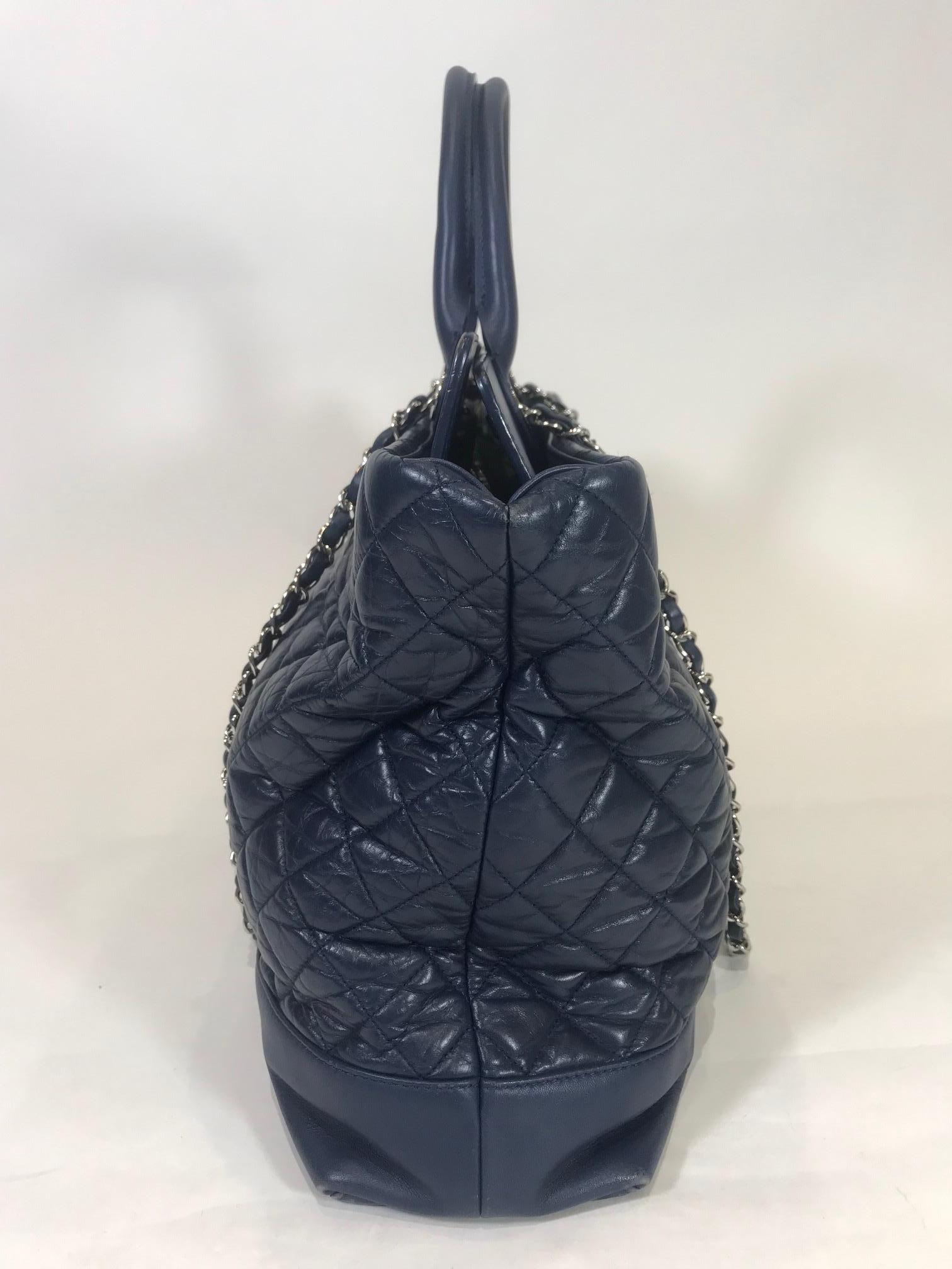 Navy blue quilted calfskin leather. Silver-tone hardware. Turn-lock closure at top. Dual woven chain-link shoulder straps with leather shoulder guard. 