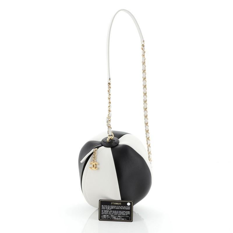 This Chanel Beach Ball Shoulder Bag Calfskin Leather Small, crafted from black and white calfskin leather, features woven-in leather chain strap with leather pad and gold-tone hardware. Its zip closure opens to a white leather interior. Hologram