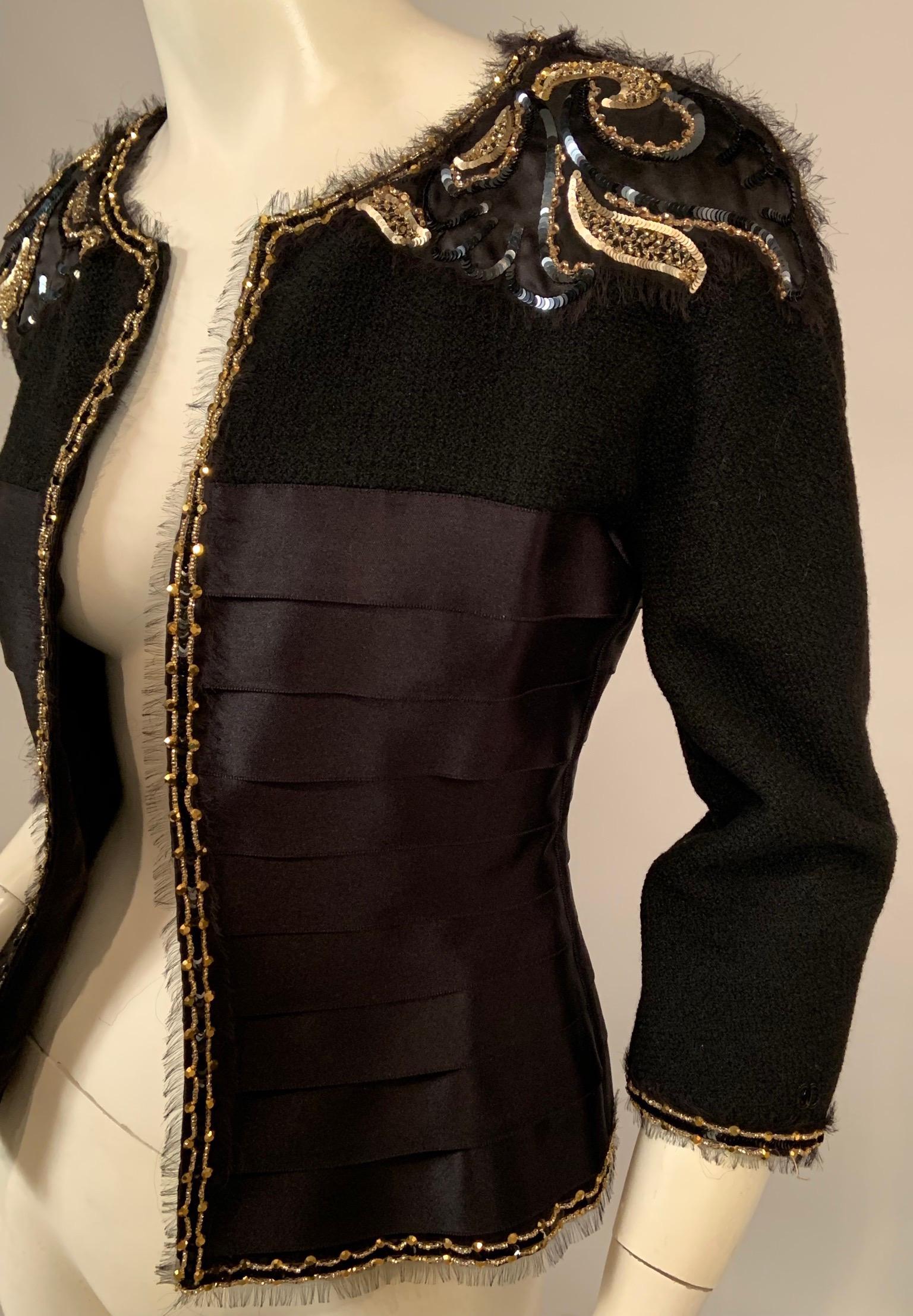 This is a jewel of a Chanel jacket, gorgeous over an evening gown and very chic with black pants or skirt. The jacket has a black wool boucle yoke and sleeves. The shoulders are appliqued with black satin that is embellished with black and gold
