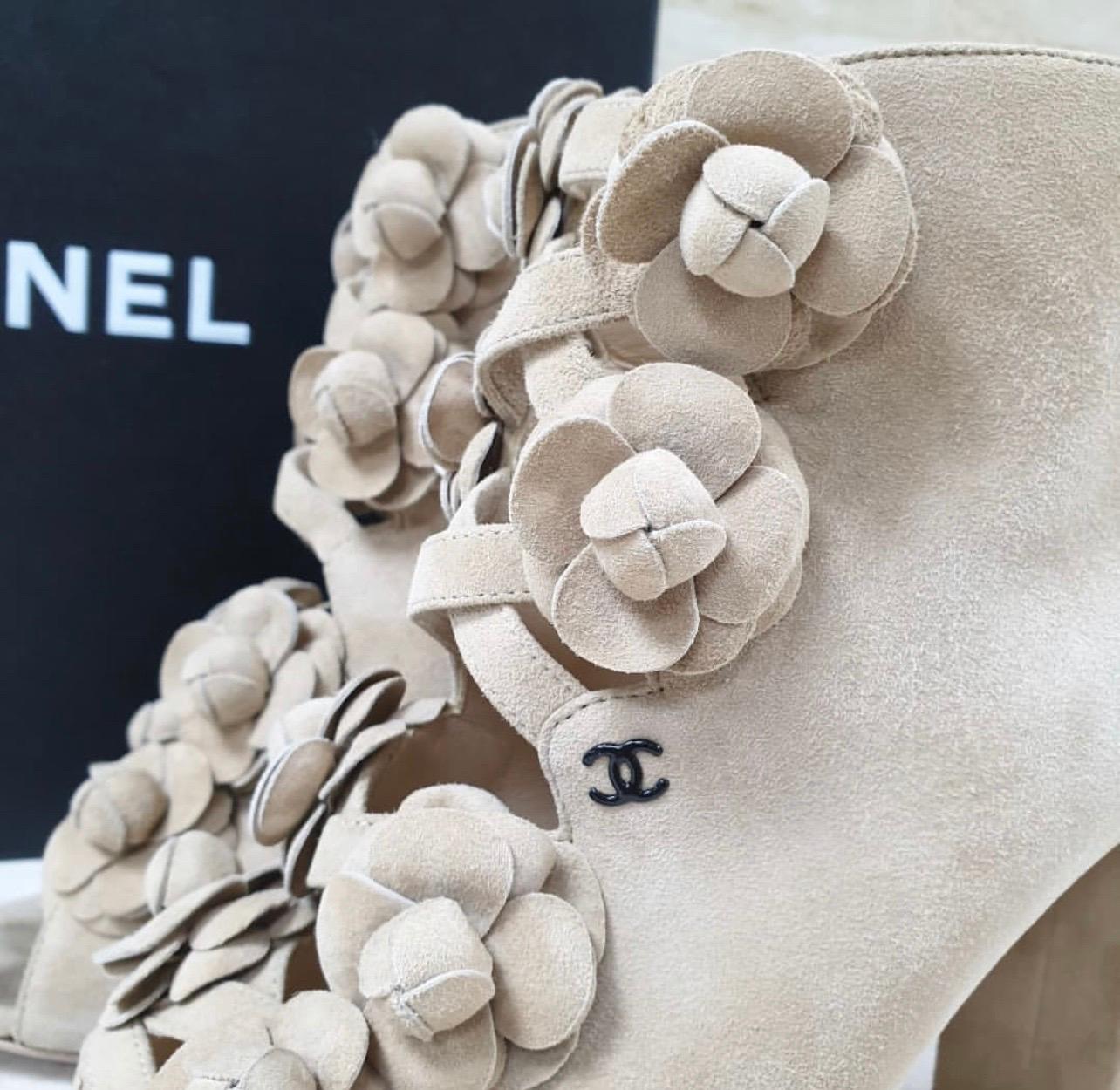 Beige suede ankle bootie features an open front with crisscross detail and open toe. 
Rows of camellia flowers on each side of the open front.
Tonal black CC logo. Heel measures 3.5