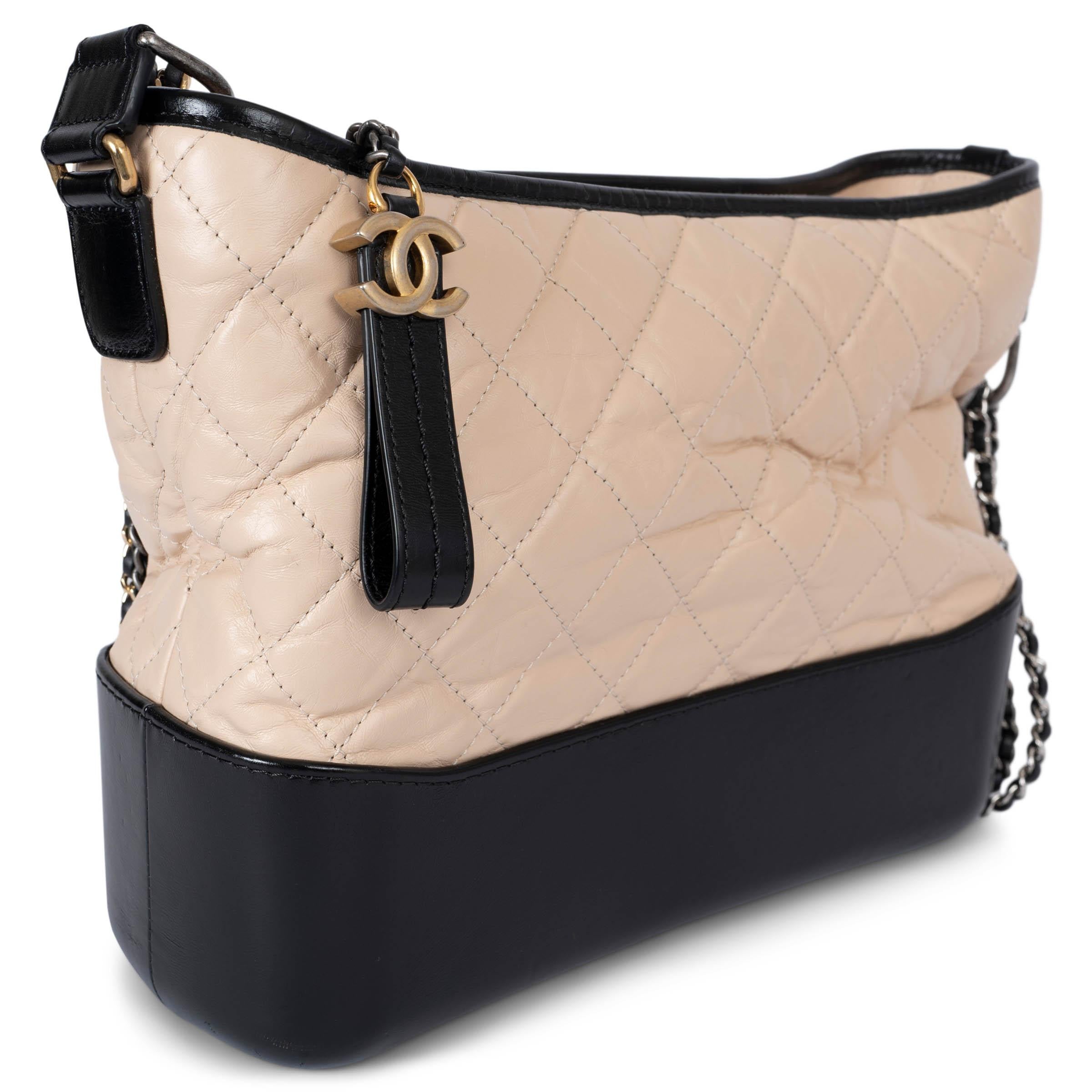 Questa borsa Chanel Gabrielle Medium Hobo, autentica al 100%, è realizzata in pelle di vitello beige trapuntata e invecchiata con finiture nere a contrasto, per un'estetica raffinata e al tempo stesso tagliente. Presenta una doppia tracolla a catena