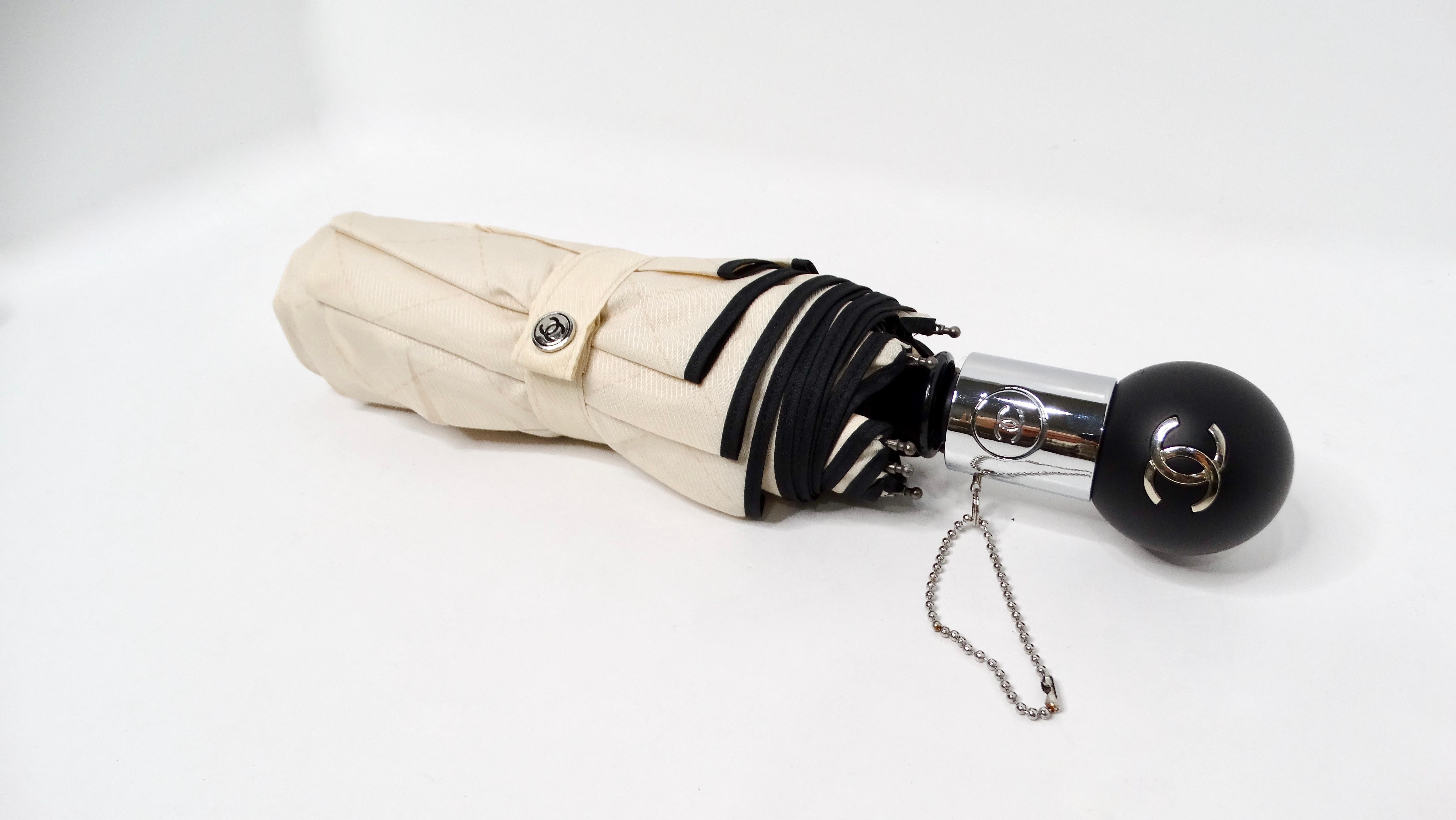 The Chanel Beige & Black Nylon Quilted Motif Umbrella is a luxurious accessory that seamlessly blends functionality with high fashion. Crafted from durable nylon, this umbrella features Chanel's iconic quilted pattern in elegant beige and black,