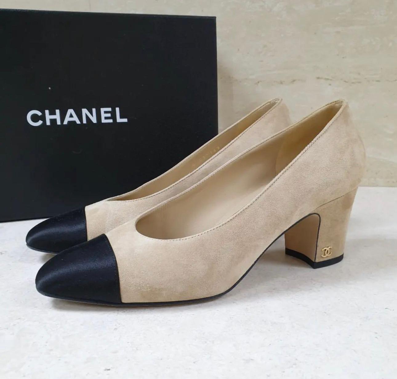 This is an authentic pair of CHANEL Suede Satin Cap Toe Low Heel Pumps in Beige and Black. 
These are a charming pair of heels that are crafted of suede in beige. 
The shoe features a black satin cap toe and a covered heel accented with a small