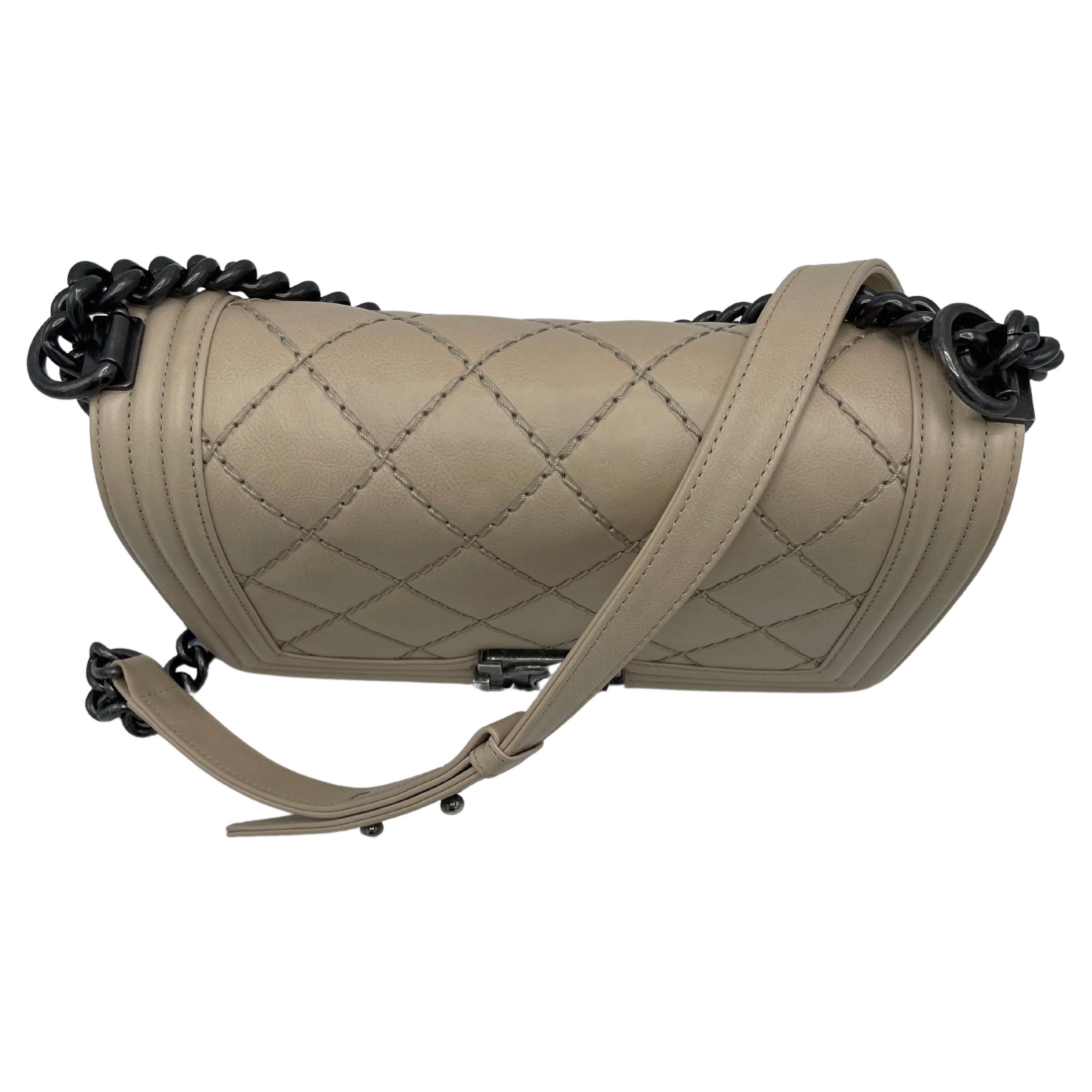 Chanel Beige Boy Flap Bag Quilted Calfskin Medium. This 2013-2014 version has a leather and chain-link shoulder strap with an adjustable buckle, a push-lock closing, and an inside slide pocket surrounded by silver hardware. Karl Lagerfeld reportedly