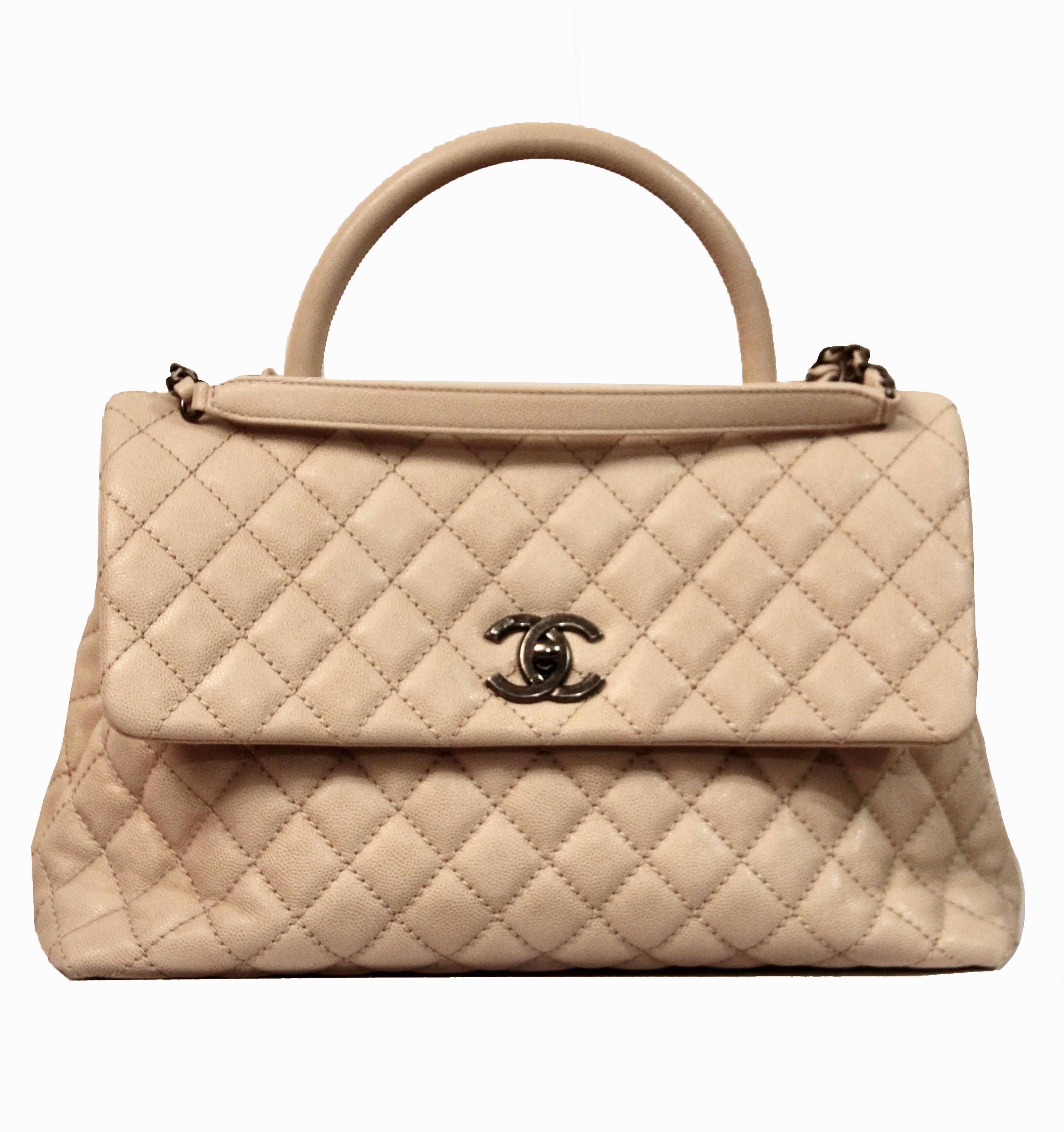 This pre-owned but new Coco Handle from Chanel is made of a beautiful beige caviar leather and features a leather top handle and a rear patch pocket, a leather threaded aged ruthenium shoulder strap. 
The ruthenium CC turn clock closure opens the
