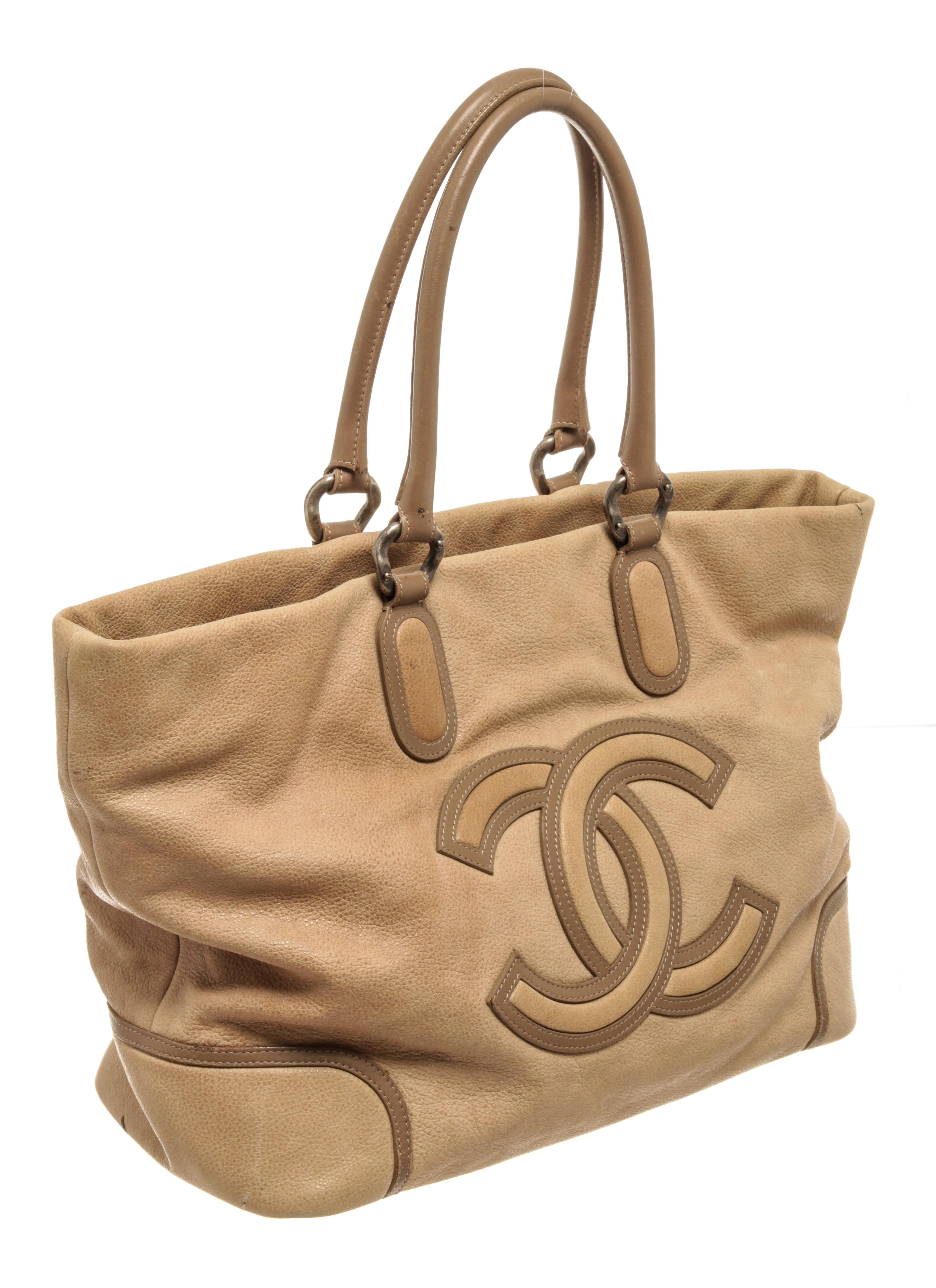 Chanel Beige Caviar Leather CC Cup Tote Bag with silver-tone hardware, metal foot base, leather trim, large CC interlocking logo at the front, black fabric lining, dual rolled leather handles, and zipper closure at the top.

75208MSC.