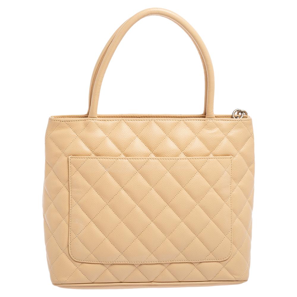 This Chanel tote is a favorite among fashionistas! Featuring the signature quilt and the 'CC' logo on the Caviar leather exterior, this beige-colored tote has a luxe look. Equipped with two handles and a spacious interior for all your essentials, it