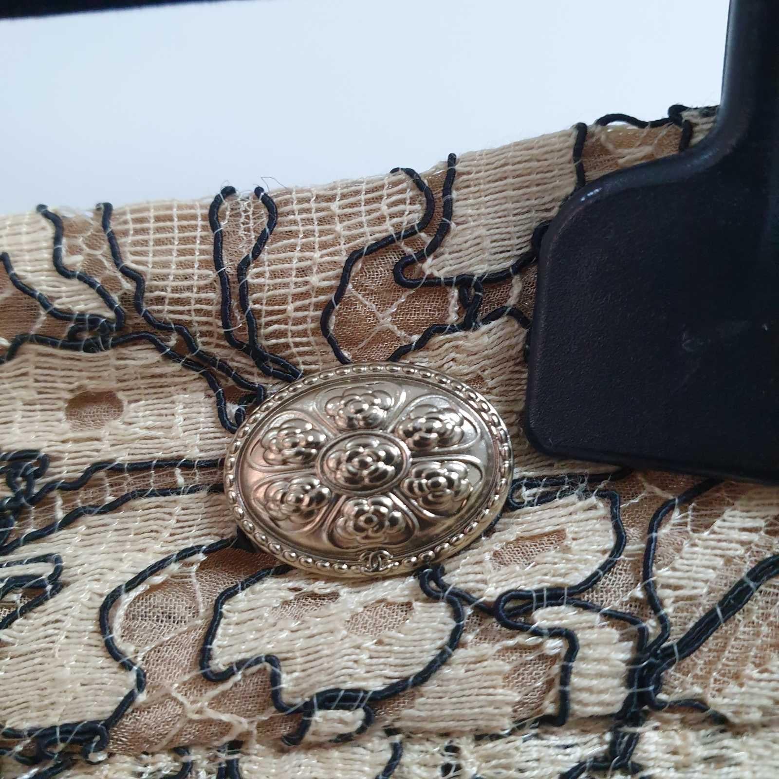 Beige and black lace skirt with flat pleats.
 
Zip fastening on the side.
Small golden oval plaque with 7 camellias sewn on the belt at the left end.
Sz.40
Very good condition.
Hanger is not included.