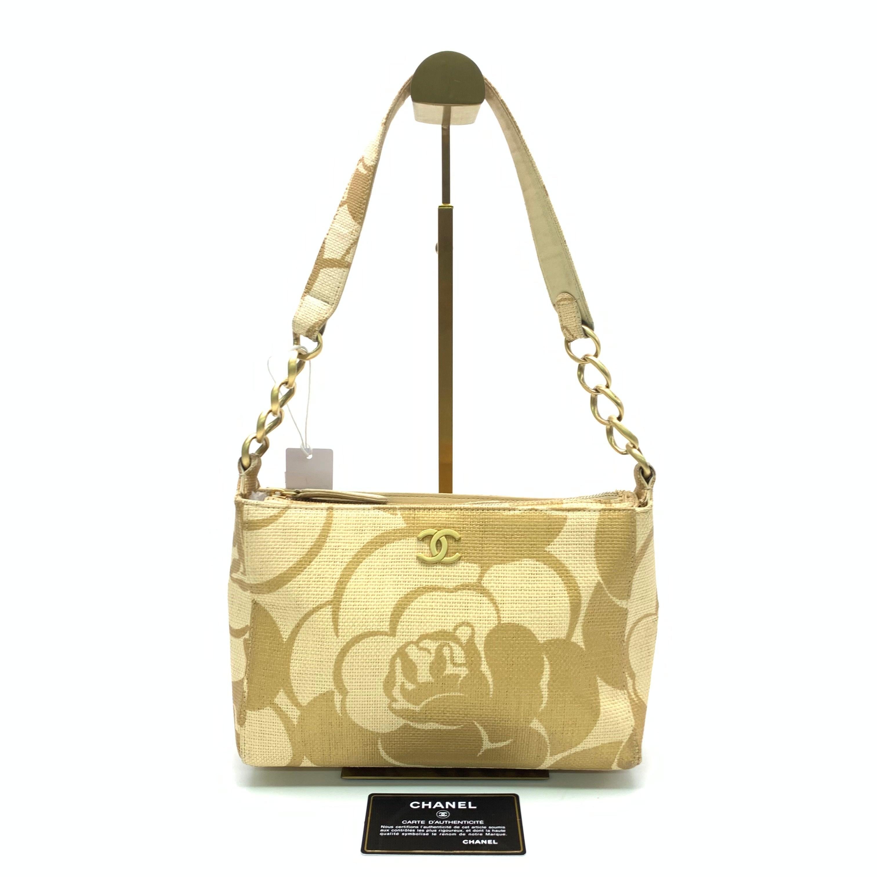 Chanel Beige Gold Woven Raffia Camellia Print Shoulder Bag, 2003-2004
These are professional photos of the actual bag.
  This Chanel shoulder bag is a perfect embodiment of luxury, showcasing the brand's signature design. Expertly crafted with