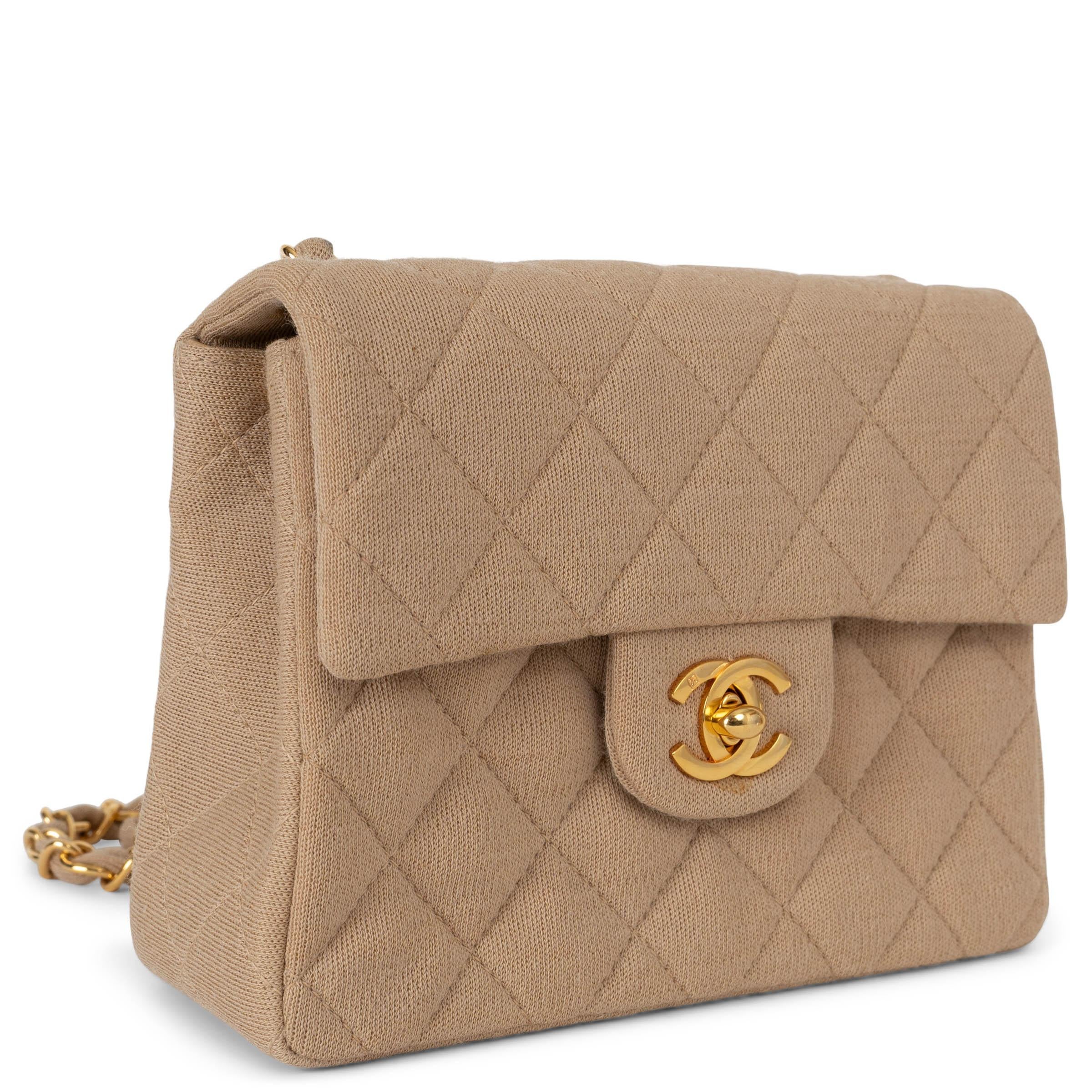 This 100% authentic Chanel Jersey Quilted Mini Square Flap in beige is an elegant, vintage shoulder bag perfect for both day and evening wear. Finely crafted from diamond-quilted jersey fabric in a classic beige, this chic mini bag features a long
