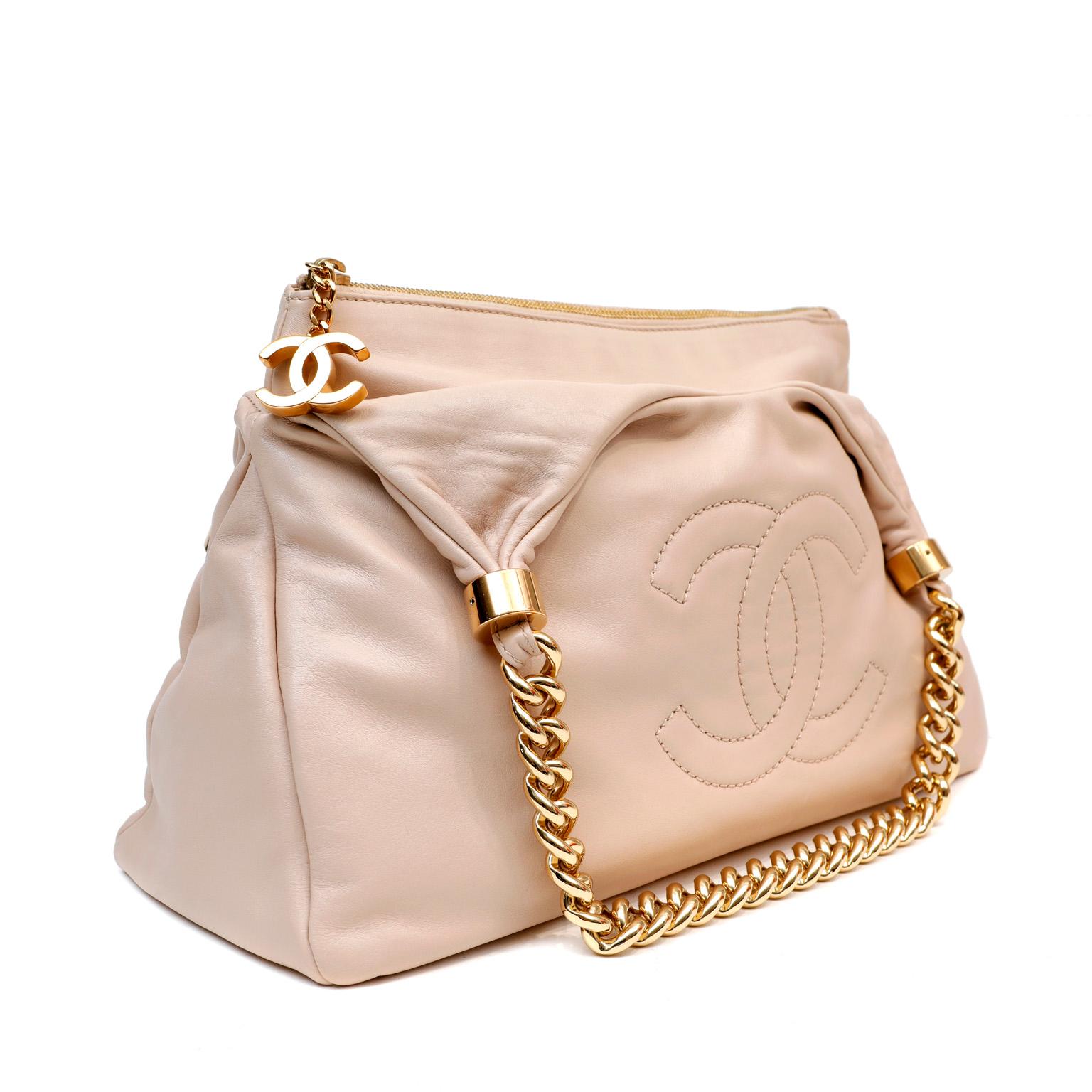 This authentic Chanel Beige Lambskin Rodeo Drive Hobo is in pristine condition.  Substantial chunky chain details and a spacious silhouette make this a perfect everyday bag for year-round enjoyment.  Supple beige lambskin hobo with large