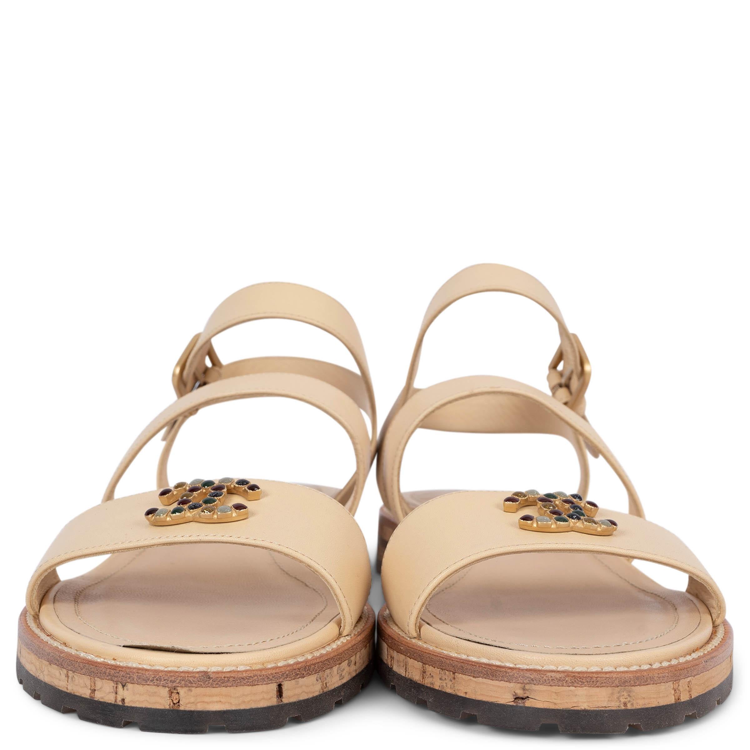 100% authentic Chanel strappy sandals in beige smooth leather featuring CC monogram appliquéd in multicolor stones. The design is set on a cork and clear rubber sole. Have been worn and are in excellent condition. 

2015