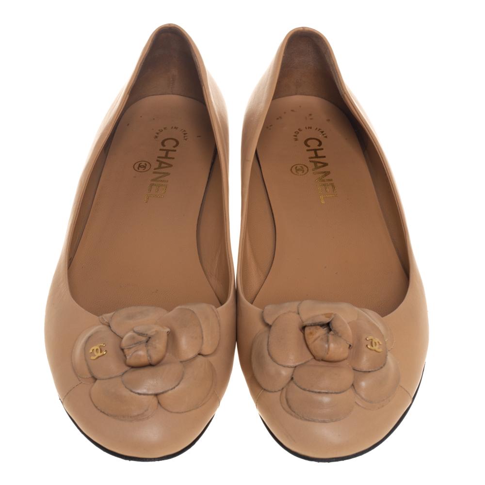 Comfort and sophistication come together when you wear these beige ballet flats from Chanel. They have been crafted from leather and styled with round toes and the signature Camellia flowers with the iconic CC logo detailed on the uppers. They are