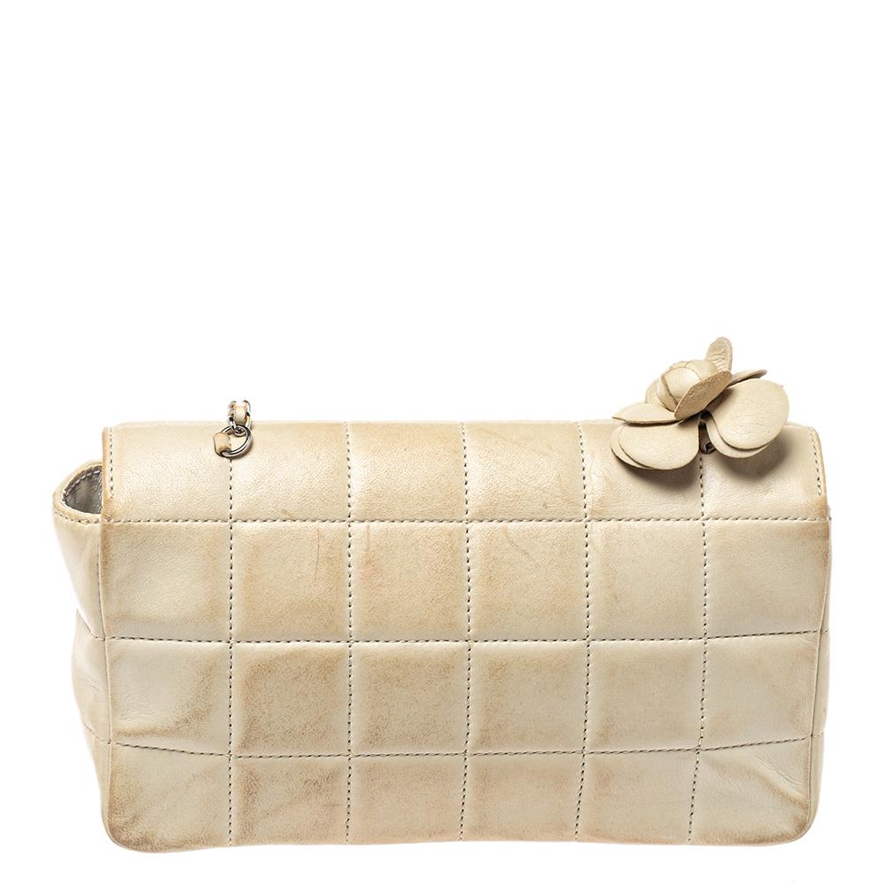 A bag to delight both Chanel lovers and handbag admirers is this one. It is made from leather and features the chocolate bar quilt on the exterior. The bag has a Camellia applique and a CC-detailed flap that secures the fabric interior. It is