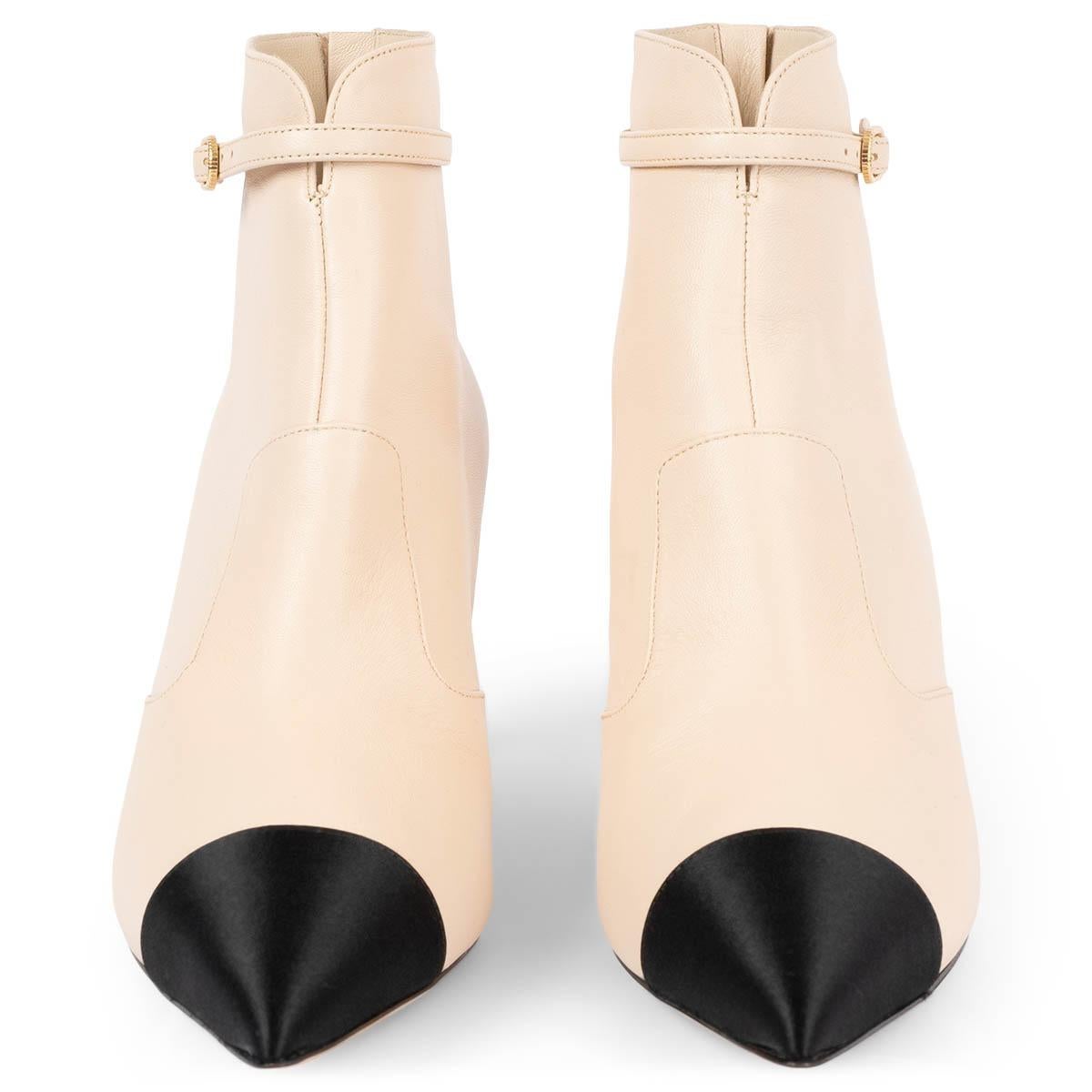 100% autentici stivaletti a punta Chanel in pelle di vitello beige con punta classica in raso nero. Il design è caratterizzato da una cerniera sul retro, un tacco impreziosito da CC in tonalità oro chiaro e una fibbia decorativa intorno alla