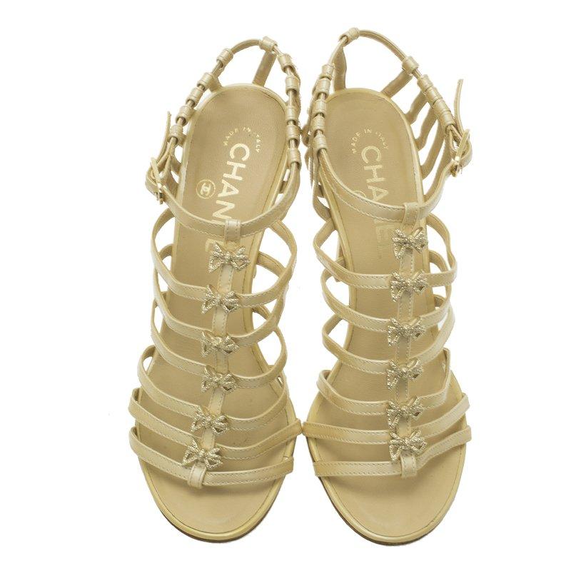 A stylish girl would love to feet herself in this elegant and eccentric pair of cage sandals from Chanel. Crafted from beige patent leather, it is adorned with bow embellishments. This pair of sandals features open toes and ankle straps along with