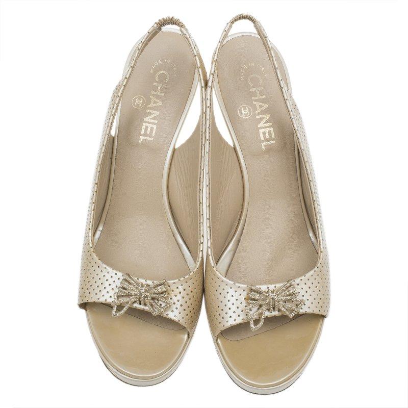 Crafted from beige perforated leather, these sandals by Chanel are timeless in their design. They feature open toes with an embellished butterfly on the vamps and slingback ankle straps. The hardware is gold-toned. The insoles are leather