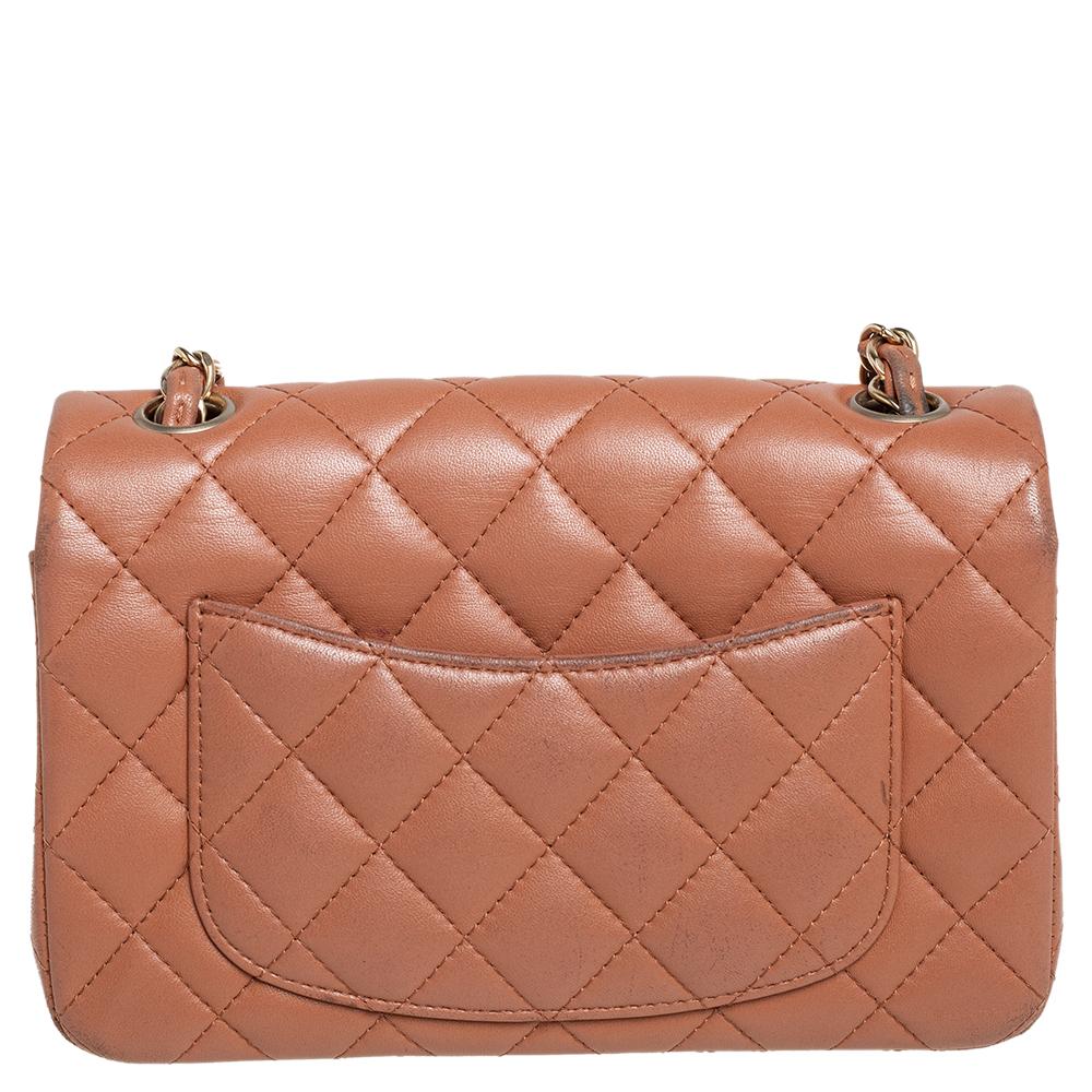 The Chanel New Mini Classic Flap Bag in beige quilted leather. It has the iconic CC lock in gold-tone metal on the flap, the slip pocket at the back, and a leather interior. The Chanel leather-chain strap completes this beauty.