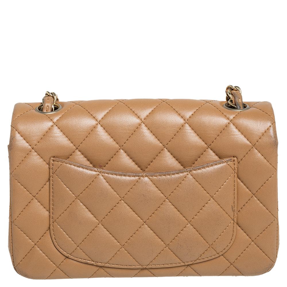 The Chanel New Mini Classic Flap Bag in beige quilted leather. It has the iconic CC lock in gold-tone metal on the flap, the slip pocket at the back, and a leather interior. The Chanel leather-chain strap completes this beauty.

