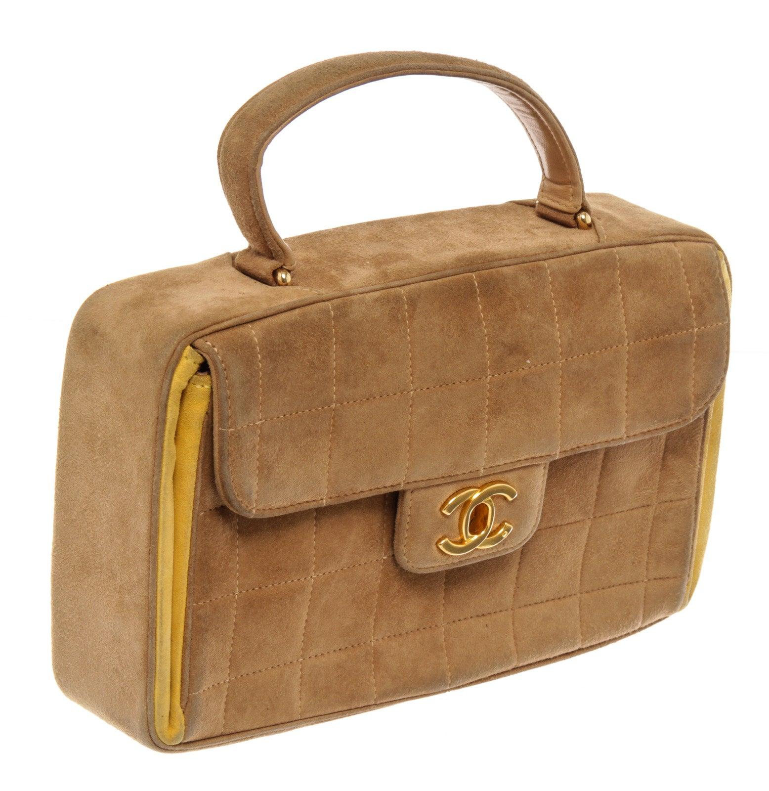Chanel Chocolate Bar CC Top Handle Bag (CC Snap Replaced) is finely crafted of smooth suede leather in light beige with bright yellow accents. The bag features beige squared stitching and a polished interlocking CC gold-tone turn lock. This opens to