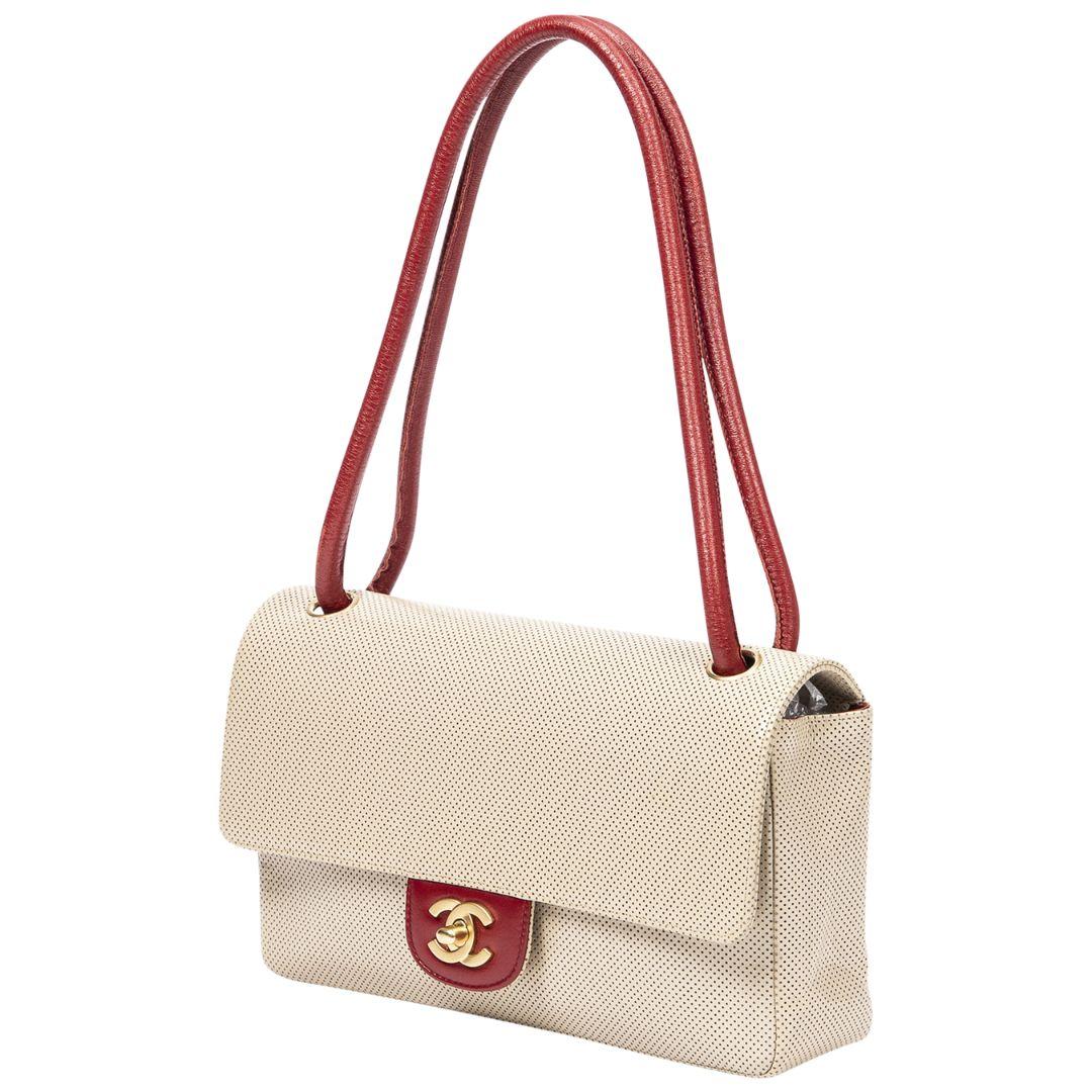 Make a bold fashion statement with this beige/red perforated leather CC turnlock flap bag. Its beige and red perforated leather design is eye-catching and chic. The gold CC turnlock hardware adds a touch of elegance to the bag's flap closure.