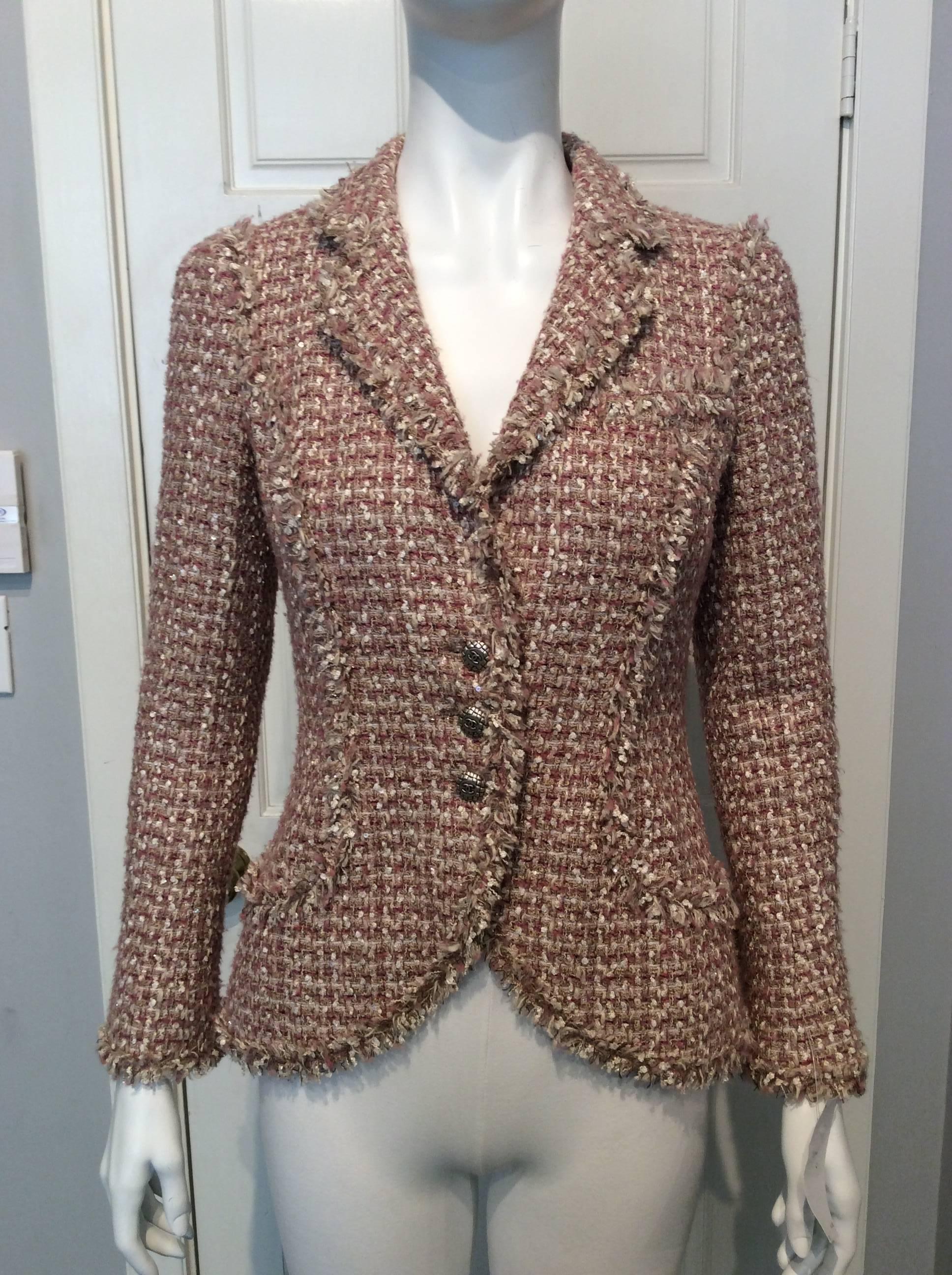 Fitted, hip length jacket in beige, ivory and rose tweed. All seams are trimmed with a fringe in the same fabric. The one breast pocket and two hip pockets are still unopened. Lined in light pink silk in the iconic camellia weave. Three silver