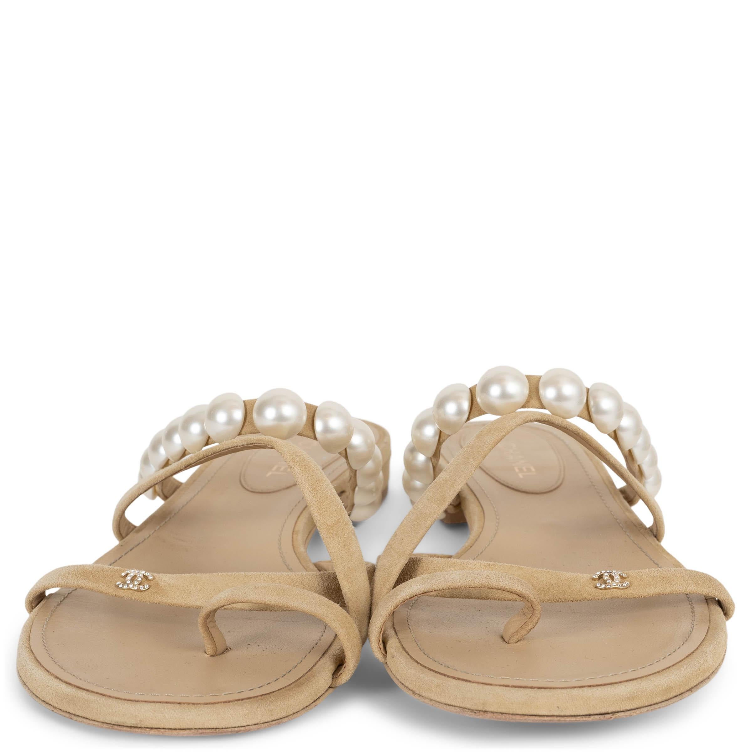 Ces sandales à glissière 100% authentiques de Chanel sont confectionnées en daim beige et présentent une bride ornée de cabochons en fausses perles pour une touche ludique et raffinée à la fois. Dotées de trois fines brides sur le devant et d'une